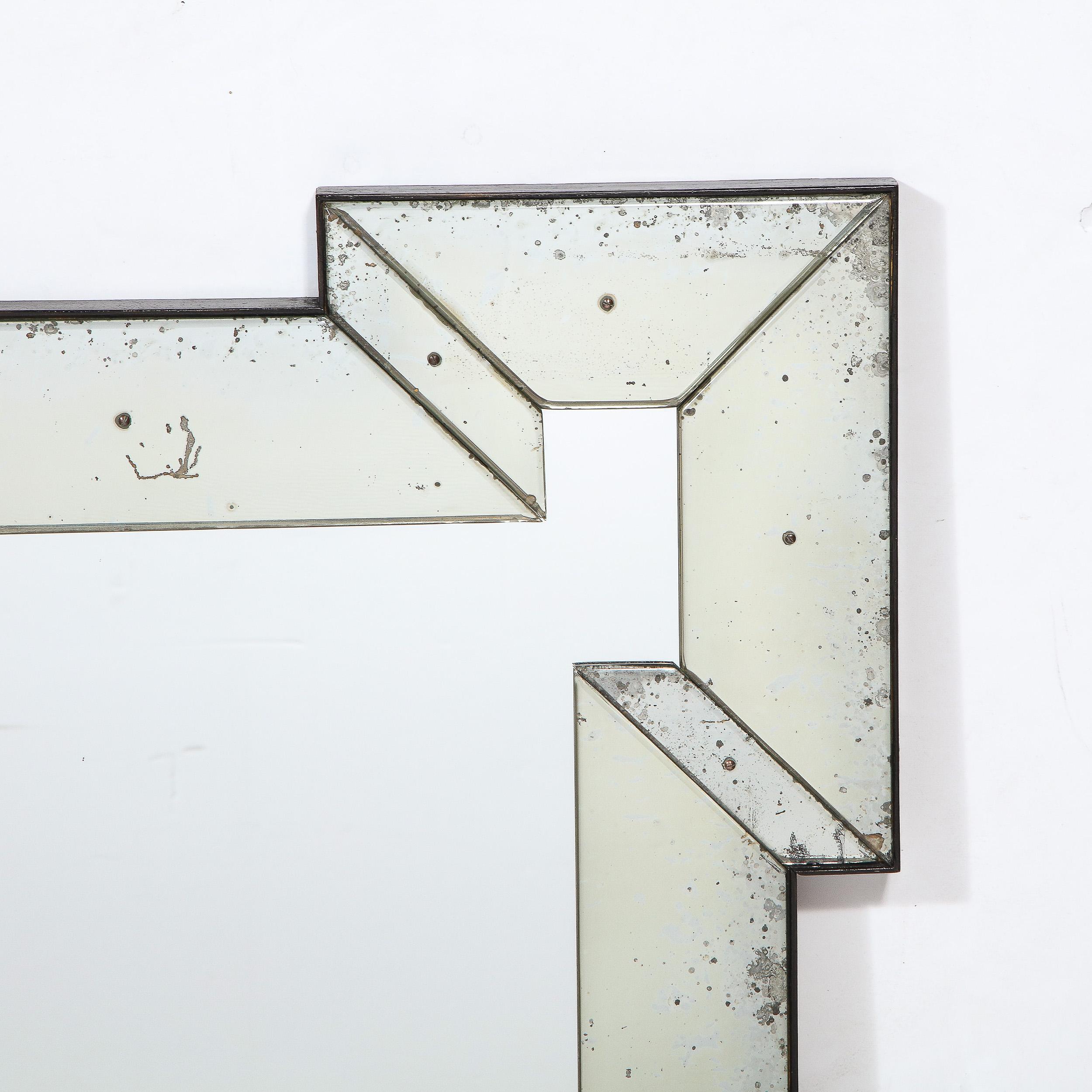 This graphic and sophisticated Mid Century Modern mirror was realized in the United States circa 1950. It features a rectangular geometric silhouette consisting of four sides with a cut-out rectangular form excised from the center of each outer