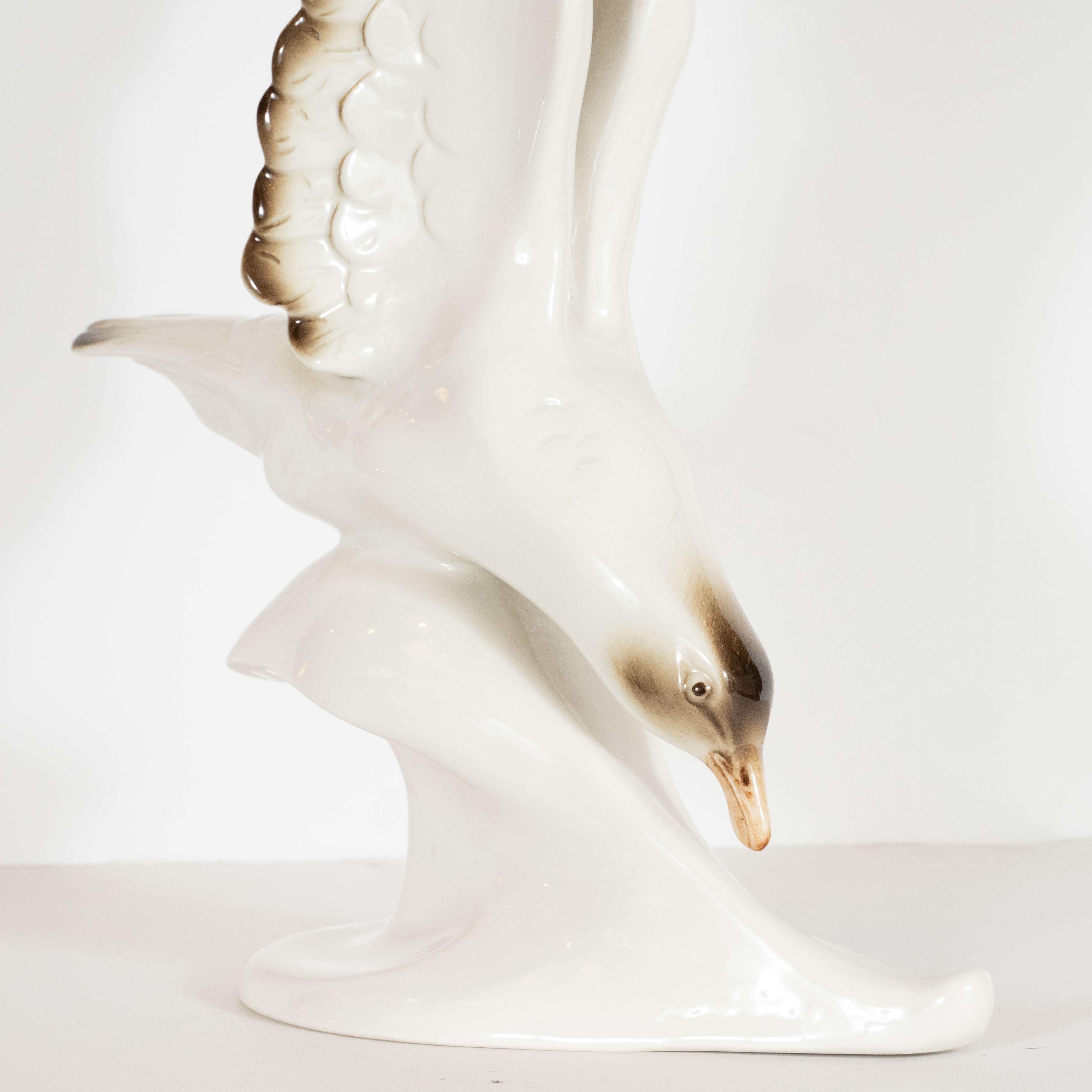 This elegant sculpture was realized by the esteemed porcelain company, Royal Dux, and hand fabricated in Czechoslovakia, circa 1950. It features a cream colored seagull with touches of sable brown on its finely articulated wings and a mocha hued