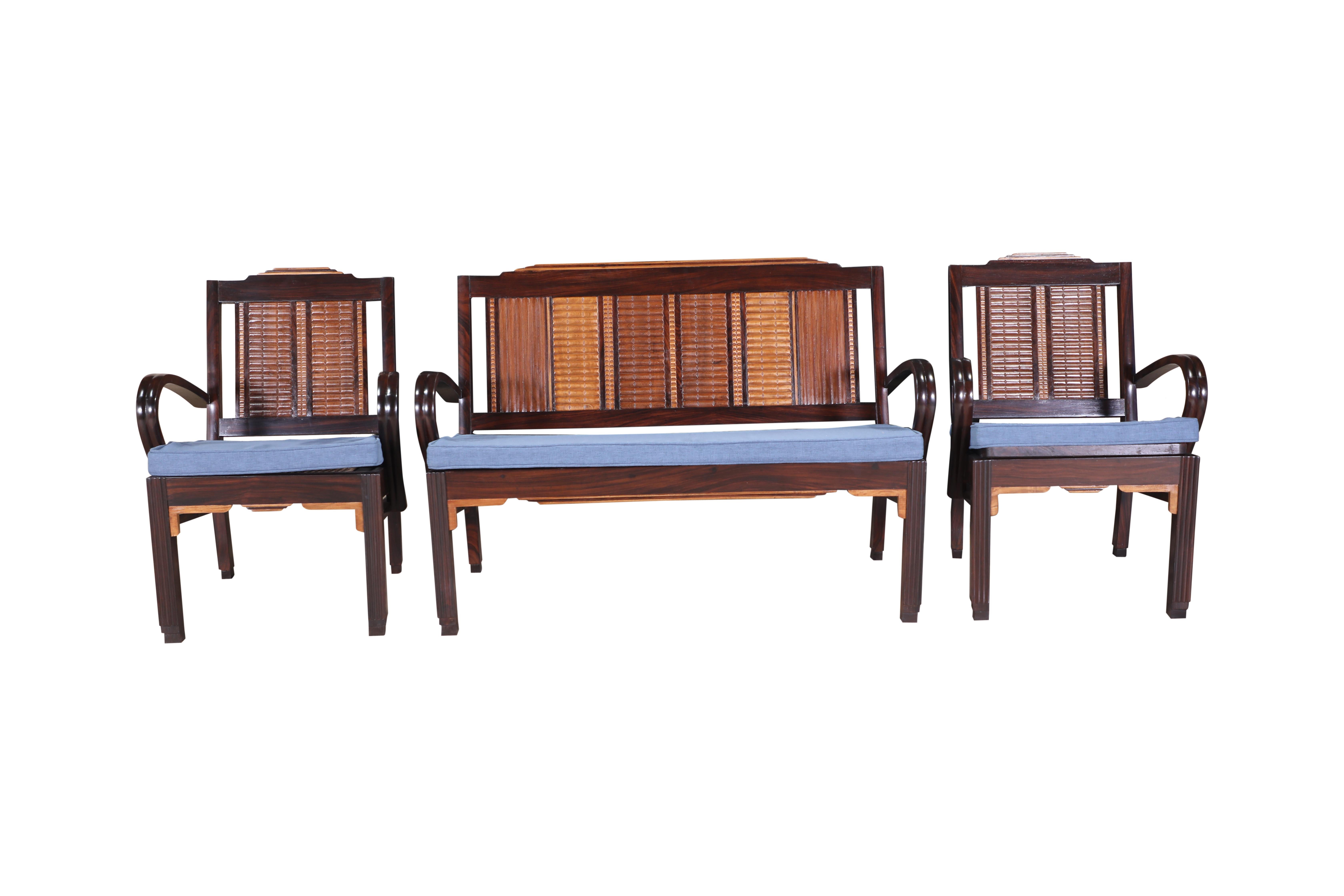 A suite of three pieces--loveseat and pair of side lounge chairs.  Carved teak, satinwood and rosewood with caned seats.  Caning is redone in a tightly woven design.  Cushions have been custom made with a medium blue silk and linen fabric with
