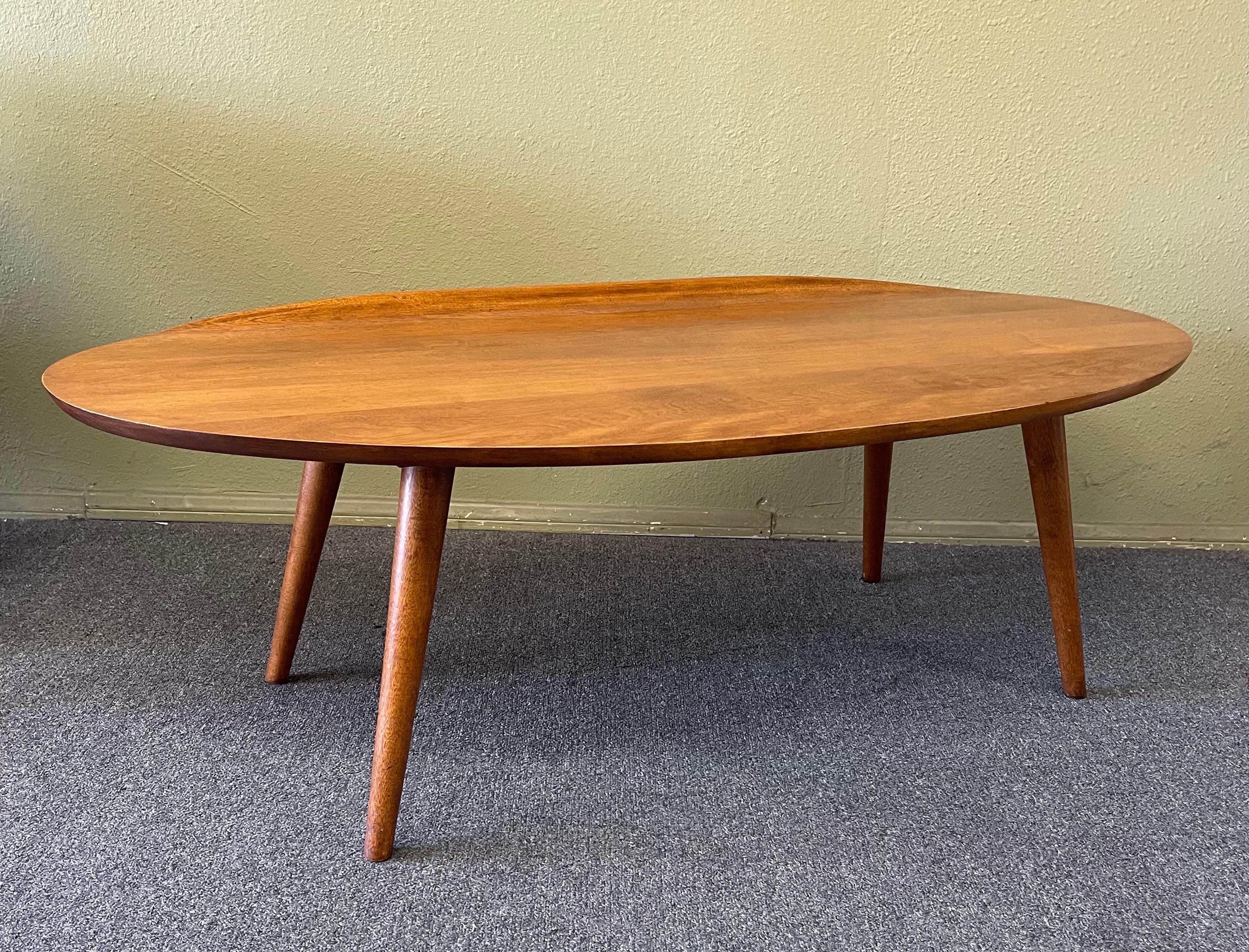 Gorgeous Mid-Century Modern surfboard coffee table by Russel Wright for Conant Ball, circa 1950s. The table has been professionally refinished and is in excellent condition. The piece is made of maple wood, has a curved edge on one side and measures