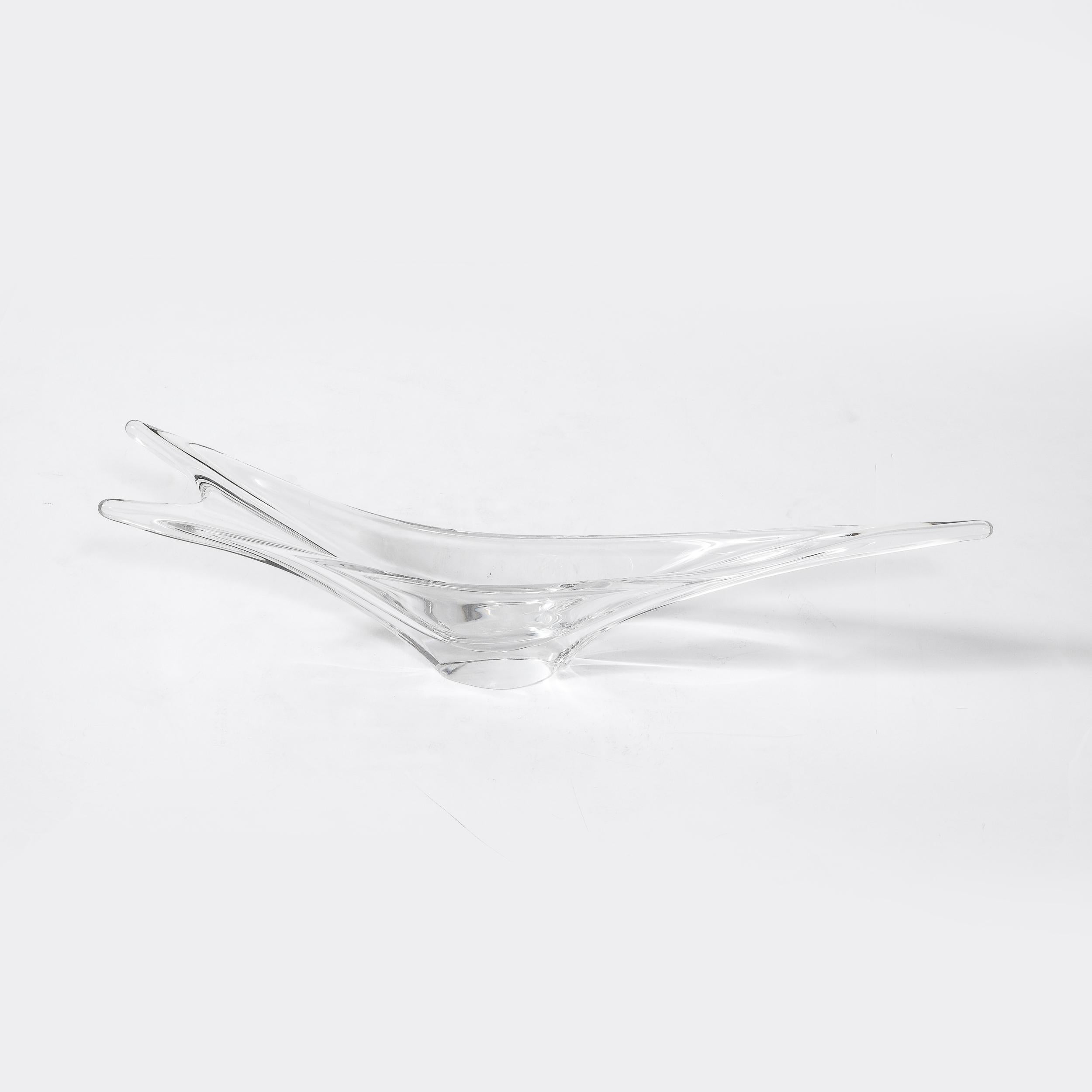 This stunning Mid-Century Modern translucent crystal centerpiece bowl was realized by the storied maker Daum in France circa 1950. It offers a stylized amorphic form with three pointed arms extending in opposite directions. One of the arms point