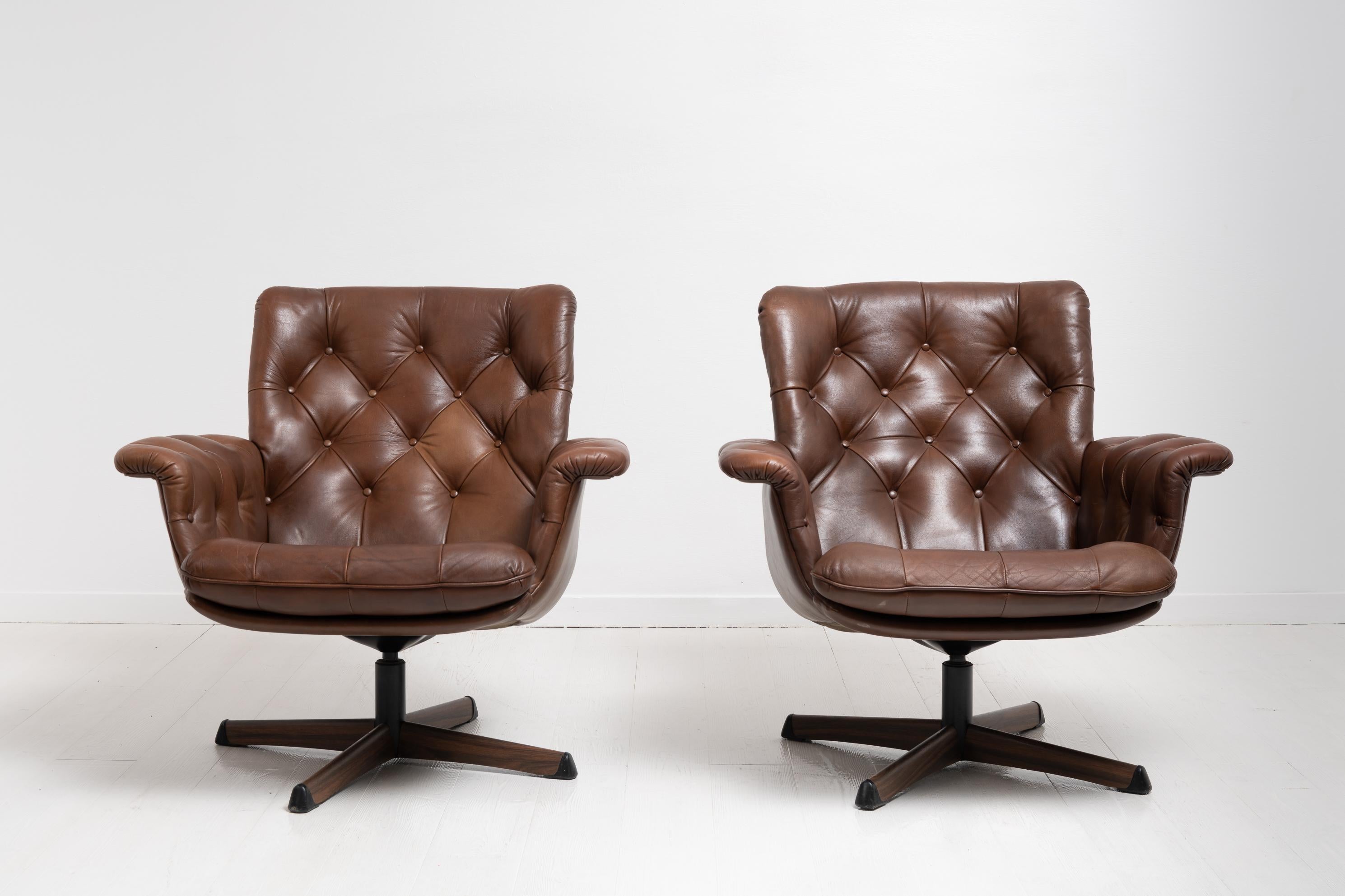 Pair of Mid-Century Modern armchairs in dark brown leather for G-möbler Nässjö. The chairs are from the 1960s with brown leather. They have a metal foot and are revolving. Loose seat cushion. The chairs are in good vintage condition consistent with