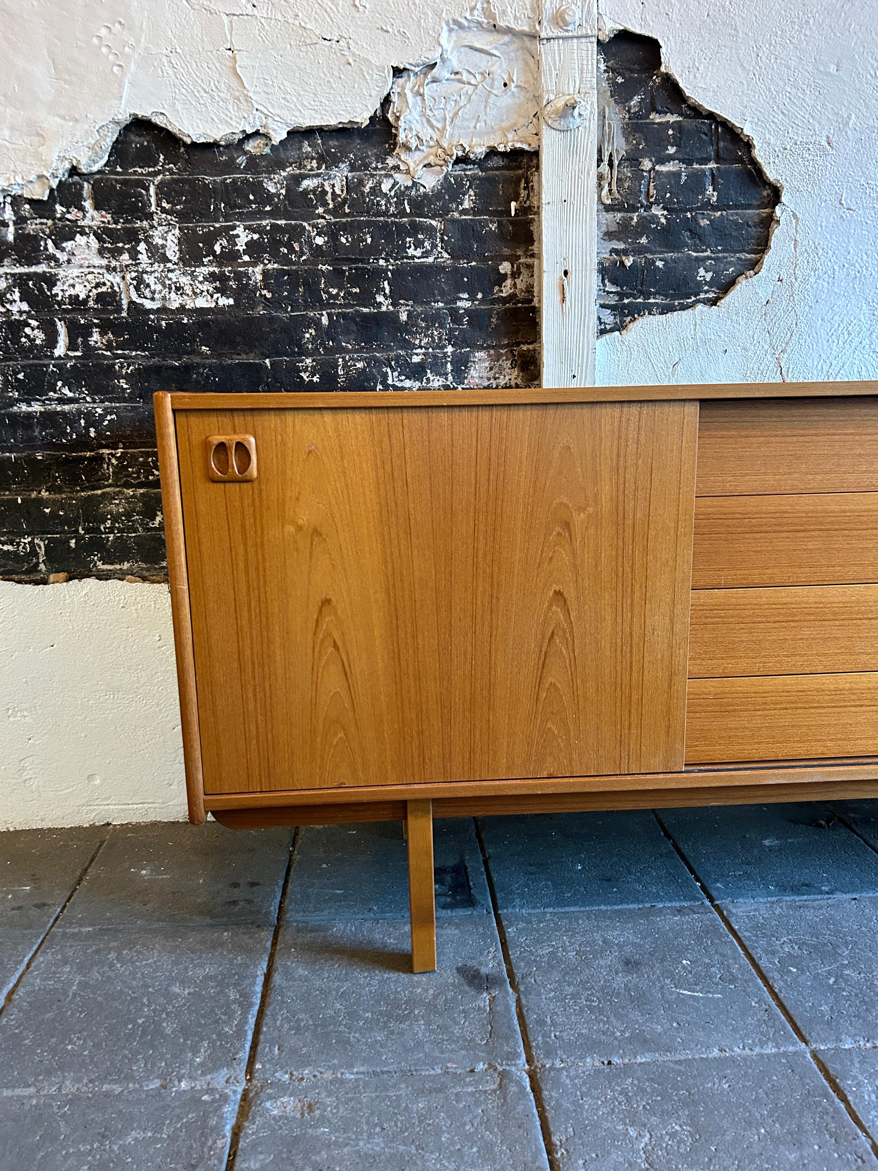 Mid Century Modern Swedish Teak Credenza with 4 drawers and 2 sliding doors by Erik Worts. Has a with a pair of sliding doors opening to adjustable shelves centering four drawers. Sits on 4 square legs. Great vintage condition. Very Clean and Ready