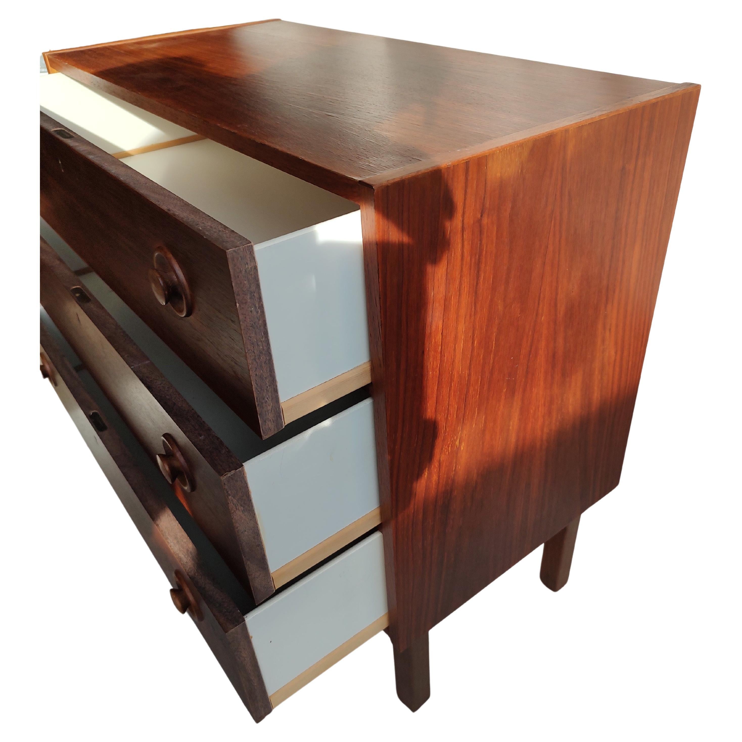 Fabuleuse petite commode en teck, simple mais élégante, avec 3 tiroirs de rangement. Petit éclat sur le bord inférieur gauche. Il sera réparé. Autrement en très bon état vintage. C'est une bonne taille pour une grande table de nuit qui serait placée