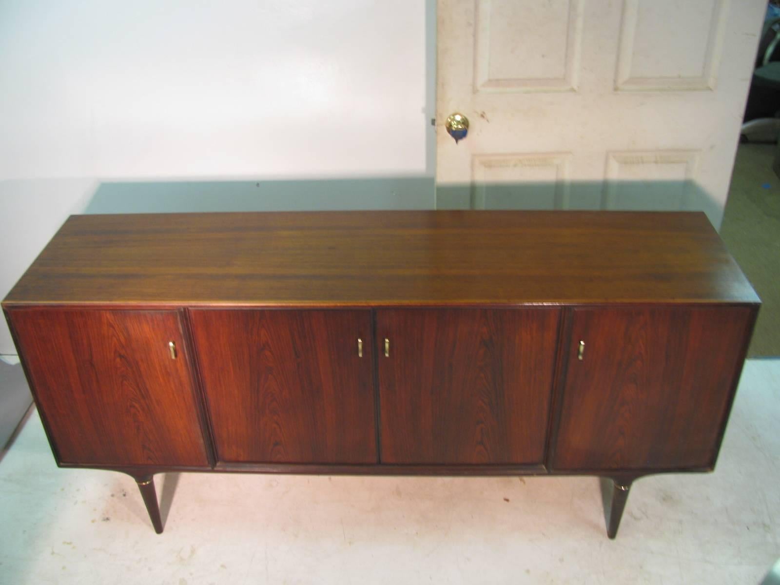 Simple and elegant four door rosewood credenza. Brass accents on the legs and door pulls along with a maple interior that has six drawers for utensils and four shelves.