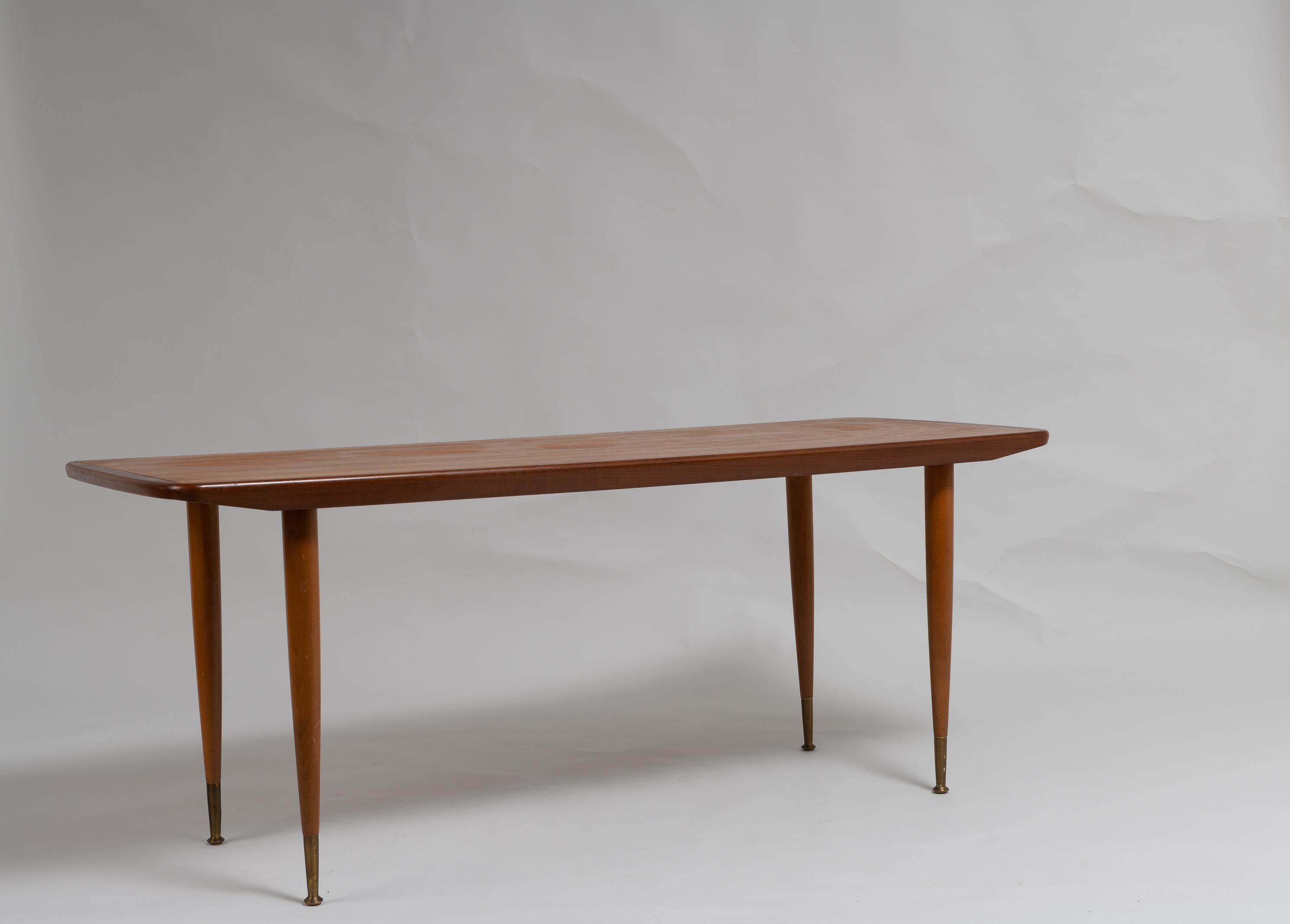 Swedish Scandinavian modern teak table from the 1960s. The coffee table has round slider legs with brass finishes. Good vintage condition consistent with age and use. The table top has some smaller scratches.
 