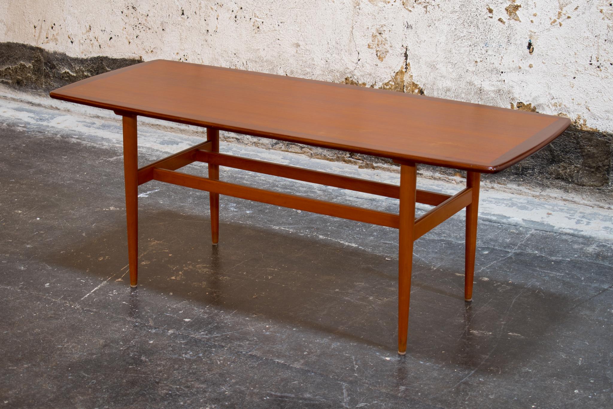 Midcentury Swedish long and slender coffee table, with dark teak border detail. Slightly rounded corners and turned legs complete the perfect mid-mod look. This elegant and understated coffee-table would work well in many design styles including