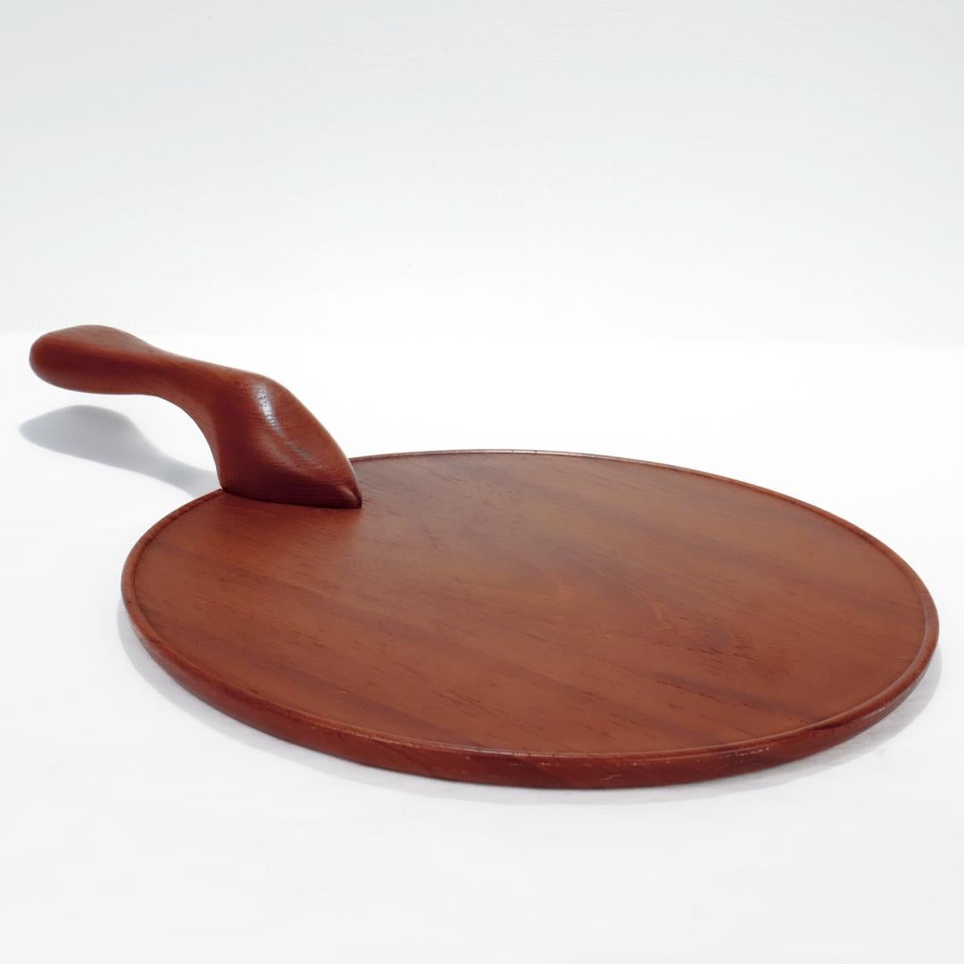 A fine Mid-Century Modern serving tray or cheese board.

In teak wood with a round tray body and a carved handle bolted to the body.

Made in Sweden.

With a maker's stamp or brand to the reverse.

Simply a wonderful, fun Mid-Century