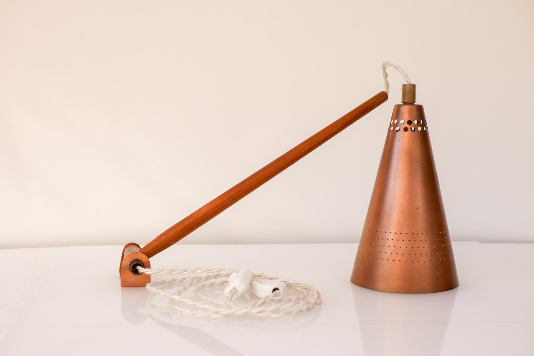 Mid-century modern classic Scandinavian swinging wall lamp made out of teak with the original copper lamp shade. The design is known as 