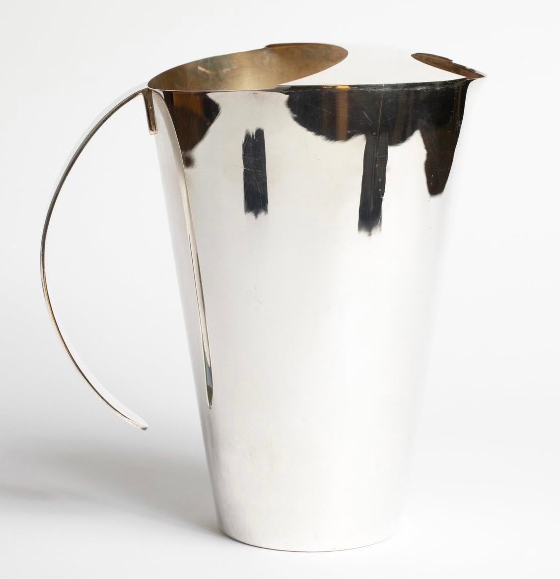 A Wonderful Pair Of Swid Powell / Calvin TsAO and Zack McKown Silver Plated Water Pitchers With A Sleek Conical Form With Flat Curving Handle And Ice Guard, This Beautiful Modern Pitcher Was Made In Italy.
DIMENSIONS: 9 1/8