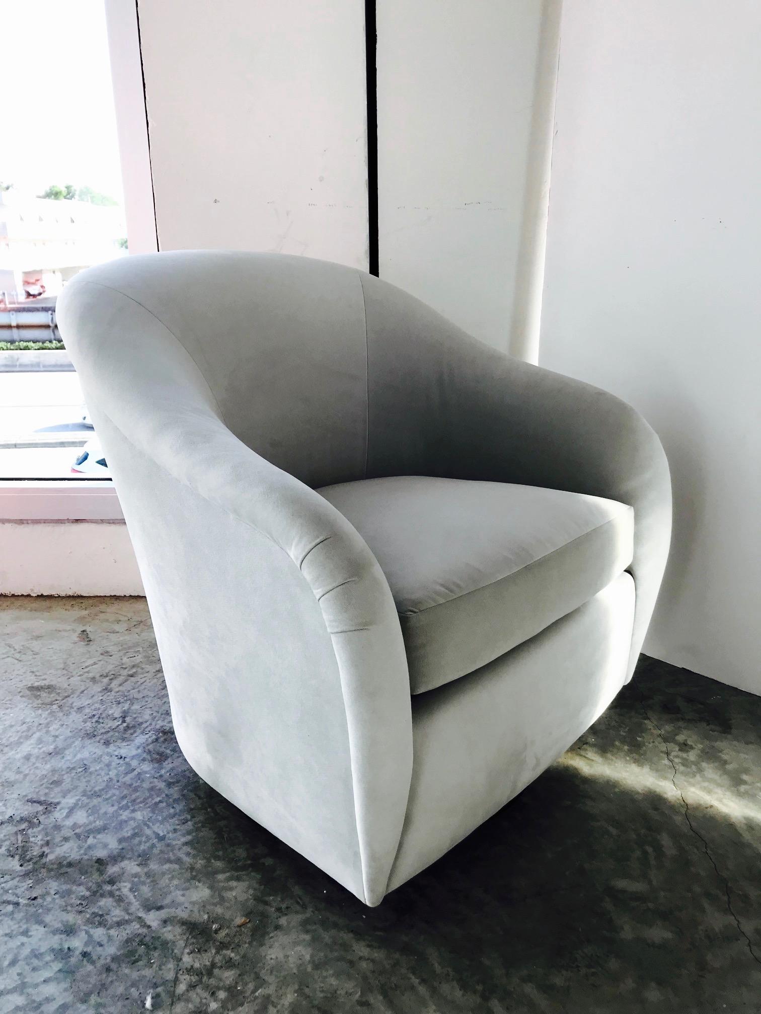 Gorgeous Mid-Century Modern lounge chair with swivel base design. Chair has barrel back form with elegant curved and tapered sides. Newly upholstered in light grey suede, or possibly fine grade microsuede, with reversible zippered seat cushion and