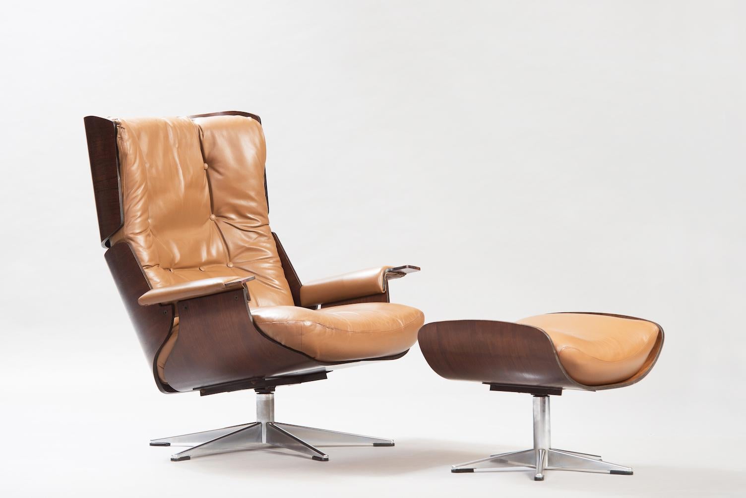 Rosewood and chrome swivel lounge chair with ottoman, upholstered in brown leather.