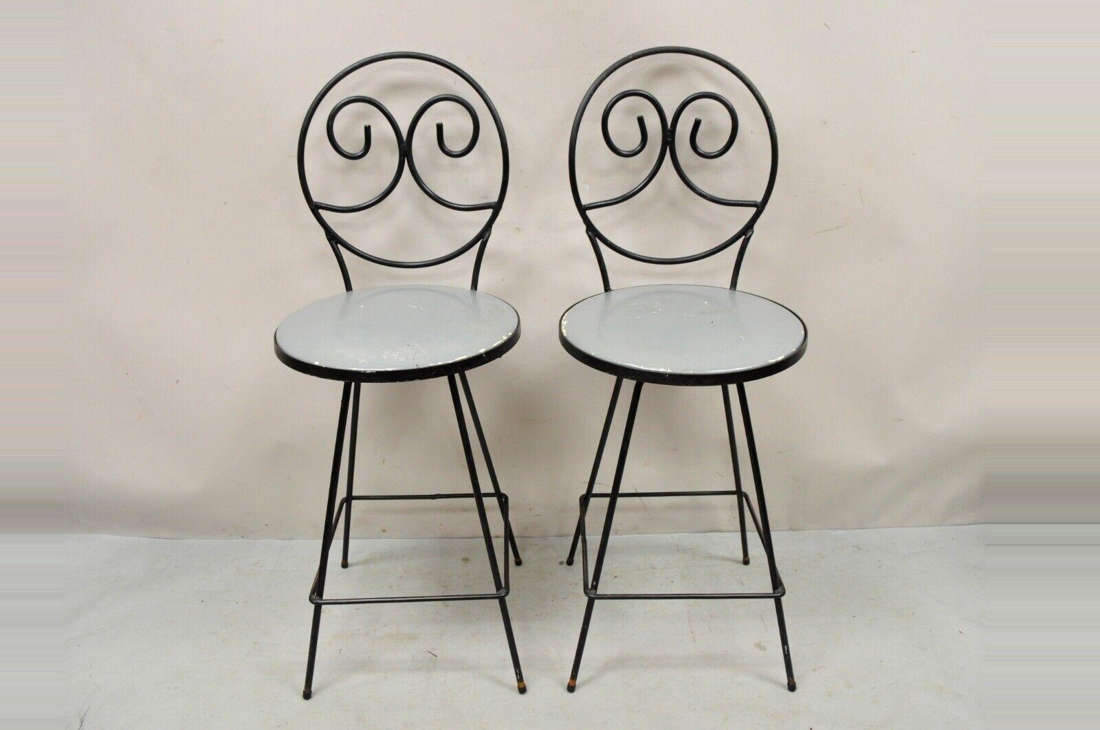 Mid-Century Modern swivel seat Arthur Umanoff style wrought iron stools - a pair. Item features swivel seats, heavy wrought iron frames, square footrests, round backs with scroll design, quality American craftsmanship, great style and form. Circa