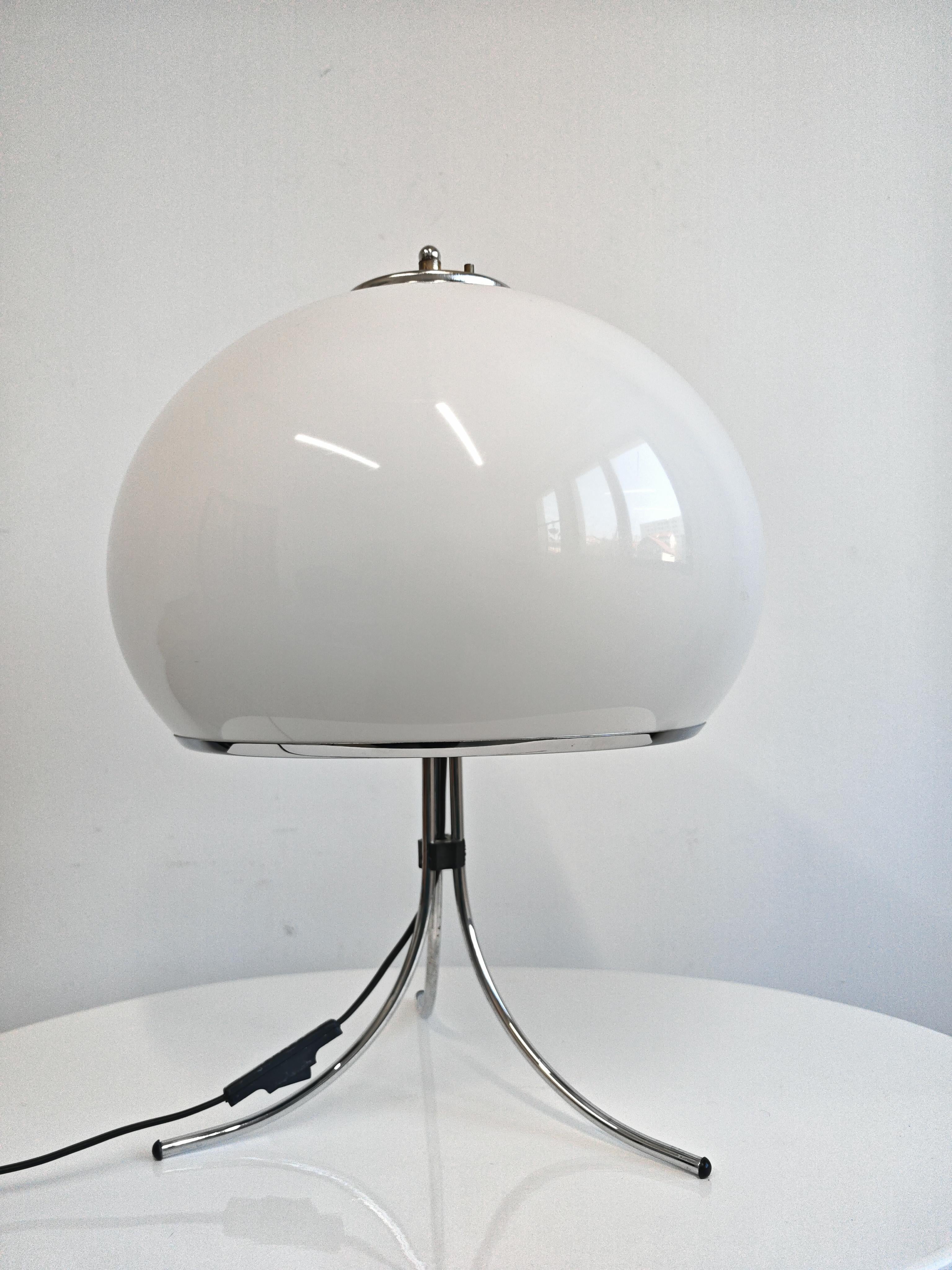 Vous trouverez dans cette annonce une superbe lampe de table du milieu du siècle ou de l'âge de l'espace, attribuée à Harvey Guzzini. La lampe se compose d'un grand abat-jour blanc en acrylique, d'un bord en acier chromé et d'un pied en acier chromé