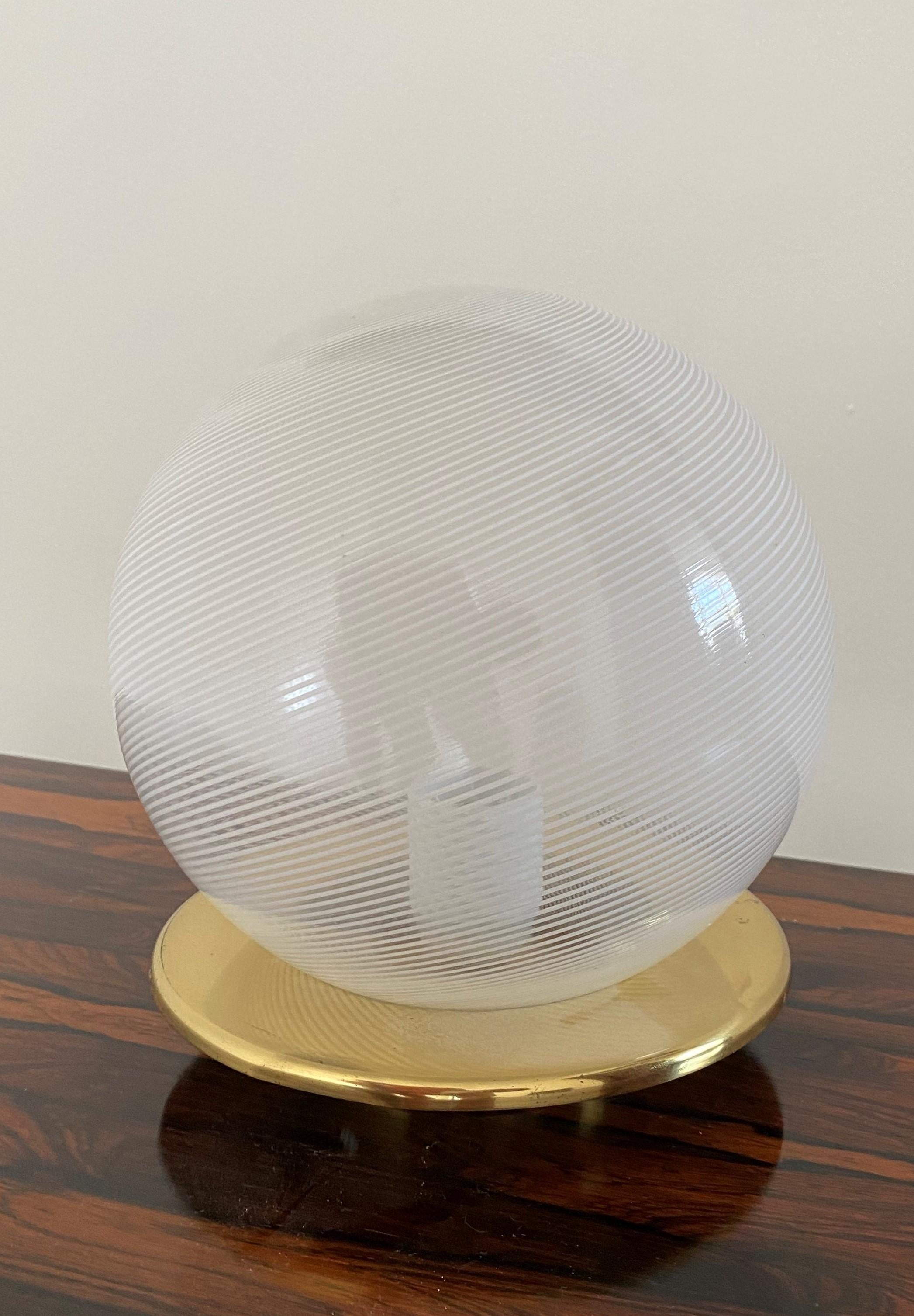 Mid-Century Modern one-light, 'Sphere' table lamp attributed to Venini, circa 1970.
Hand blown in the 'Tessuto' and swirl technique in white and clear murano glass, with a brass base.
It holds one E14 bulb.
 