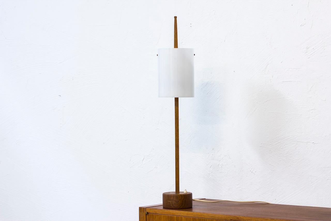 Rare and tall table lamp designed by Uno & Östen Kristiansson for their own company Luxus at Vittsjö, Sweden during the 1950s. Solid oak base and stem with acrylic shade. 2 light sources. High quality in the making. Signed with label.