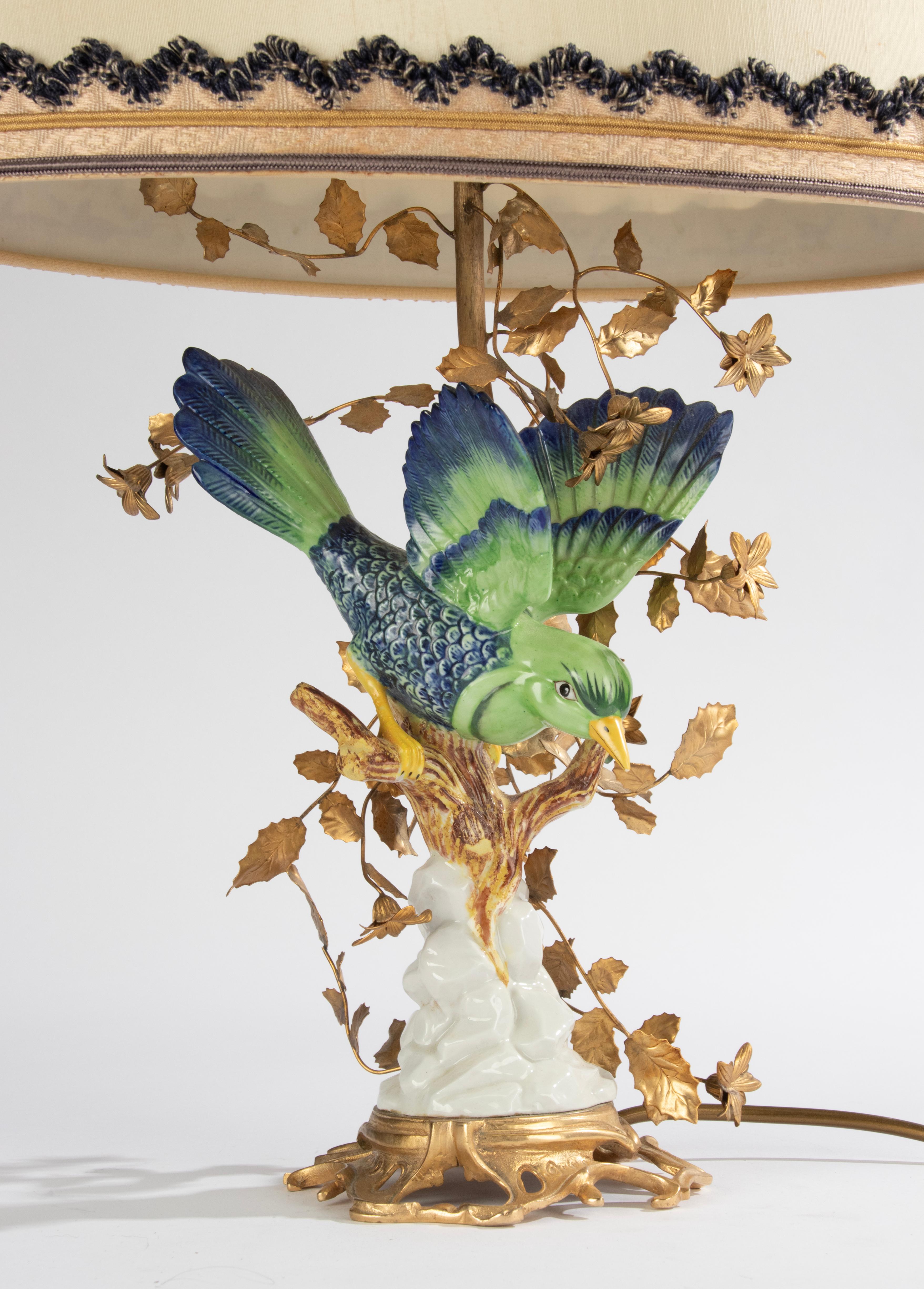 Magnificent luxurious table lamp of a tropical bird with a large gilded bush. 
Created by the Italian brand Giulia Mangani, circa 1960-1970
The bird and pedestal are made of porcelain and bear a sèvres style stamp on the back.
The tree/shrub is made