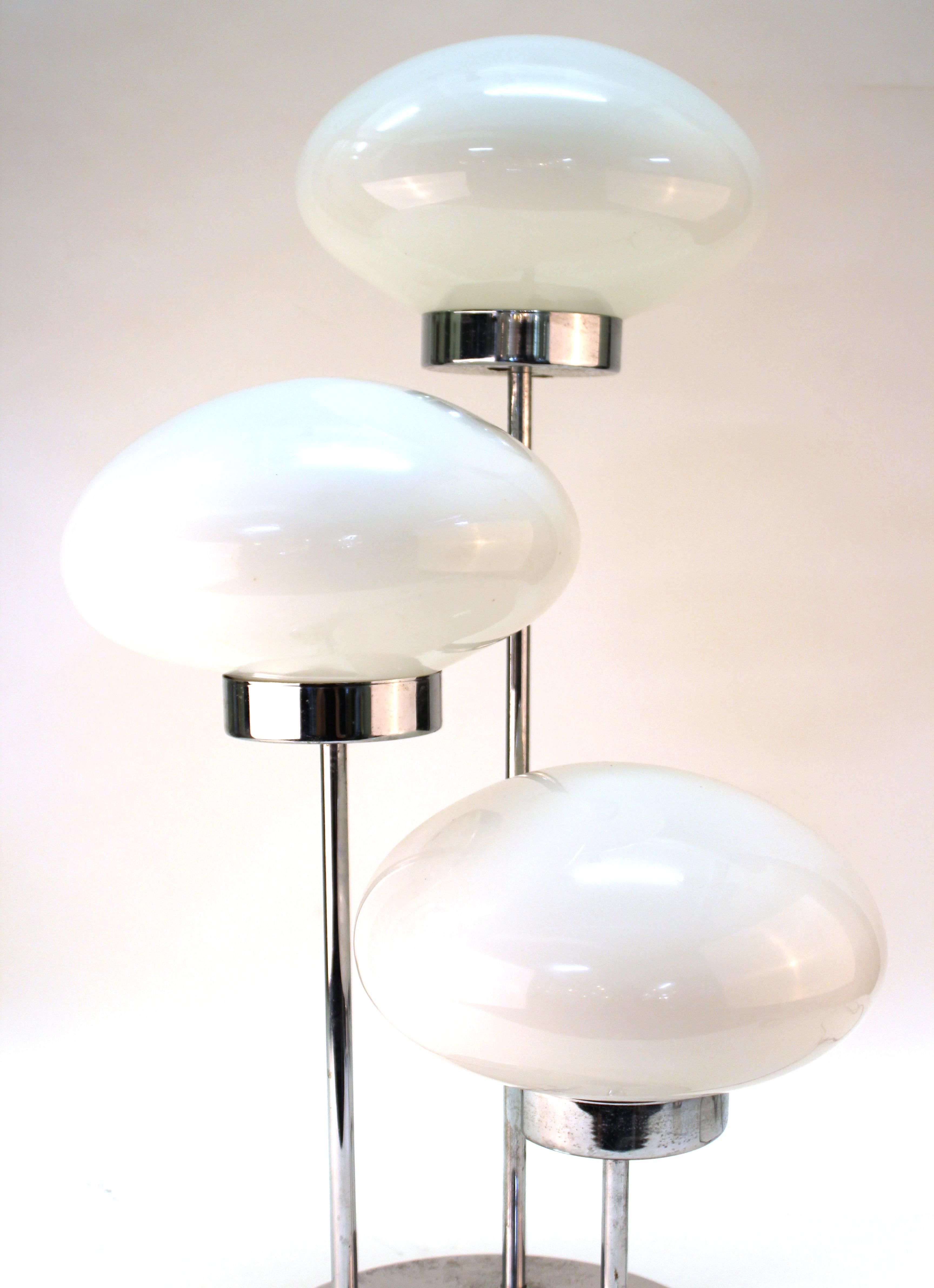 Mid-Century Modern period table lamp in chrome featuring three domed light sources in white glass. The piece has some age-appropriate wear and patina to the chrome as well as some small old paint drops on the white glass lights.