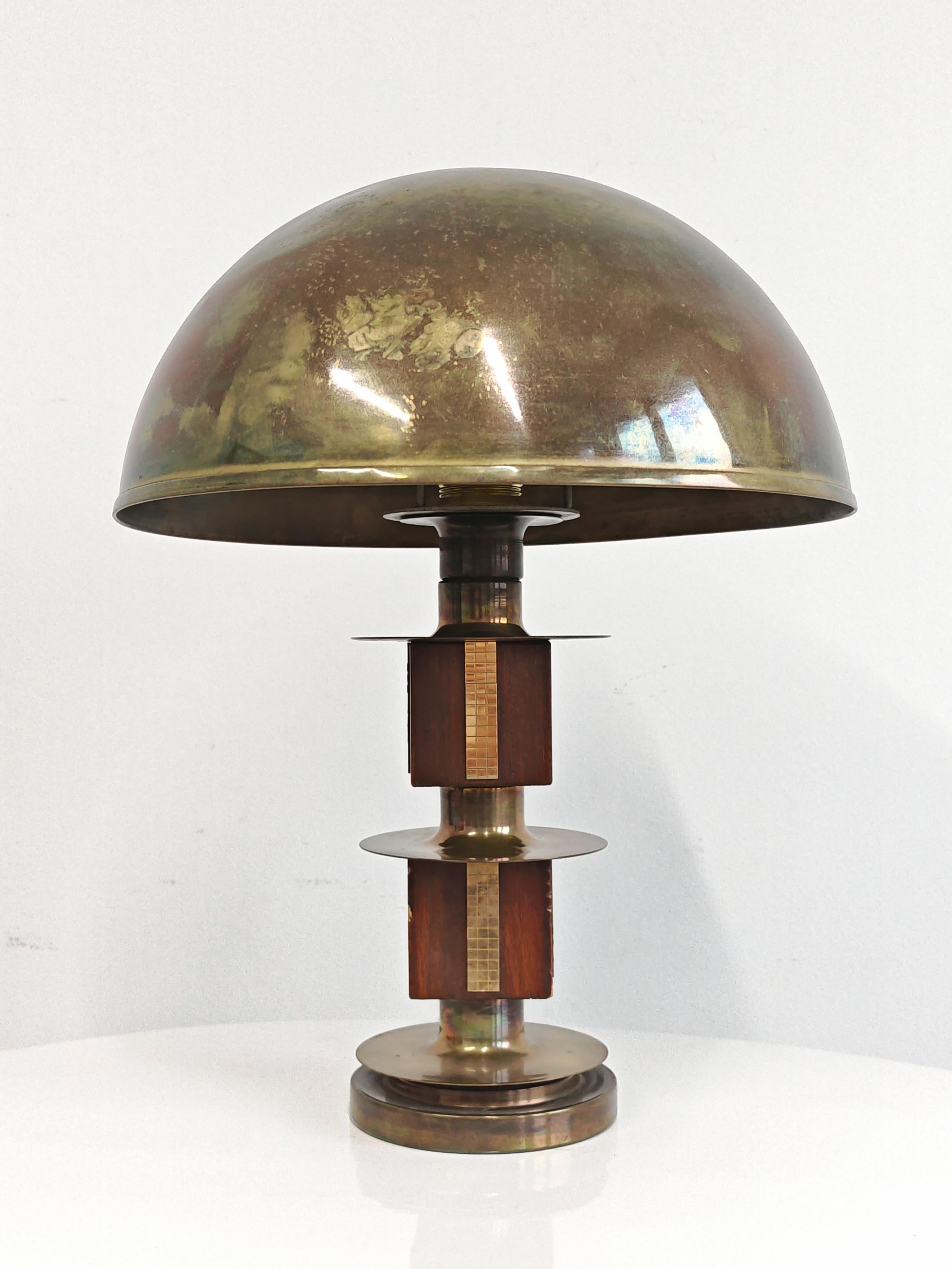 En este anuncio encontrarás una impresionante lámpara de sobremesa Mid Century Modern. Presenta fuertes elementos geométricos: una pantalla en forma de cúpula de latón, una base circular y el estambre realizado en varios cubos de caoba y latón. La