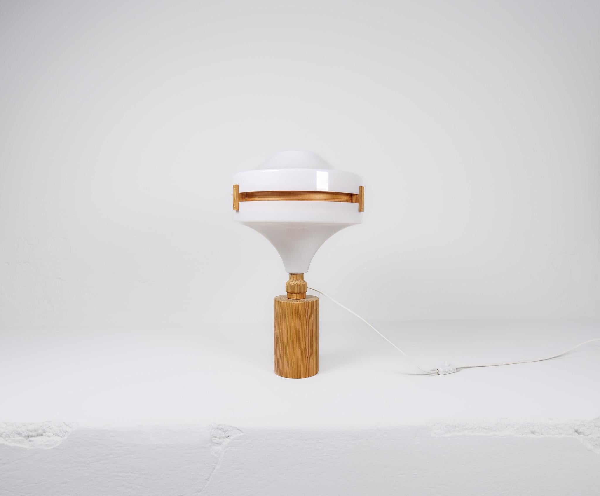 A nice-looking table lamp made with rounded solid pine base, ending with an acrylic white top. The inside of the shade is gifted with rounded thin pine. 
Made in Sweden during the late 60s or early 70s, this lamp gives a nice edition to any modern
