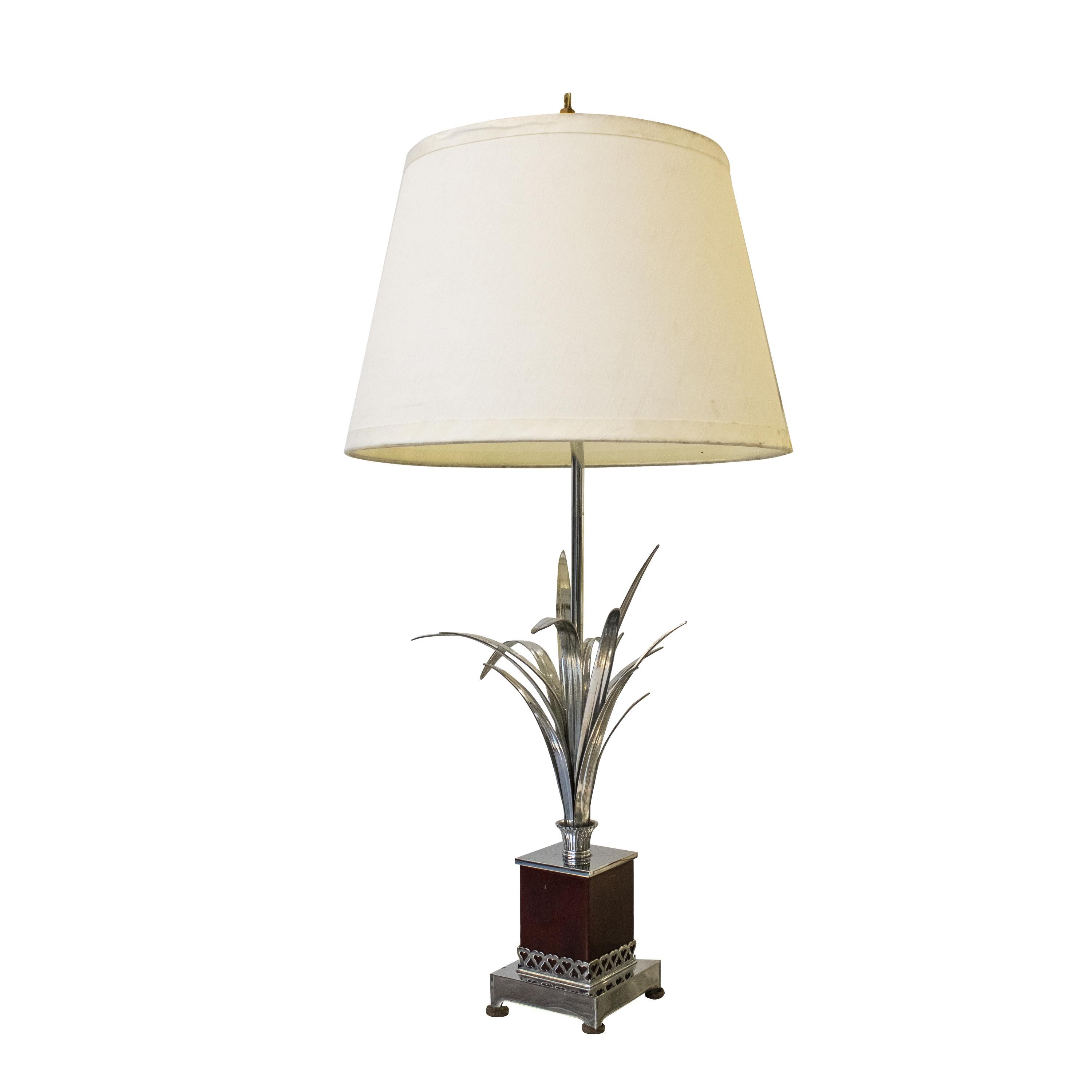 Italian steel table lamp from the 1960s. It is composed of a rectangular steel base with four support points. The base (2) is covered in burgundy plastic and hurt-shaped ornaments. This lamp's leg is made of metal a tube with sculptural leaves