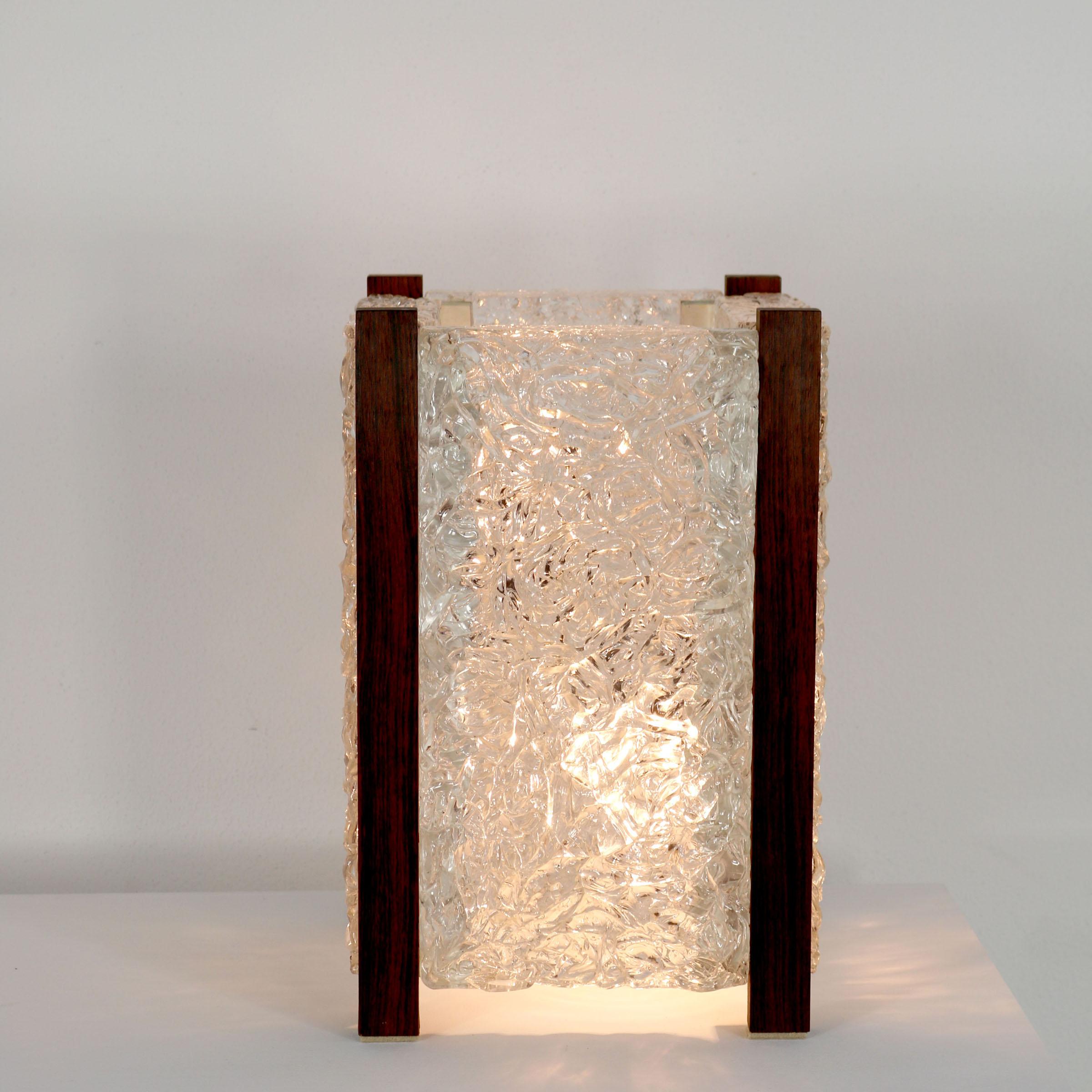 Elegant rectangular Mid-Century Modern table lamp with thick textured acrylic glass and rosewood frame. Designed and manufactured probably in Scandinavia, 1970s.
The lamp is in working condition, 2 x E14 bulb sockets. Pleasant warm light tone and in
