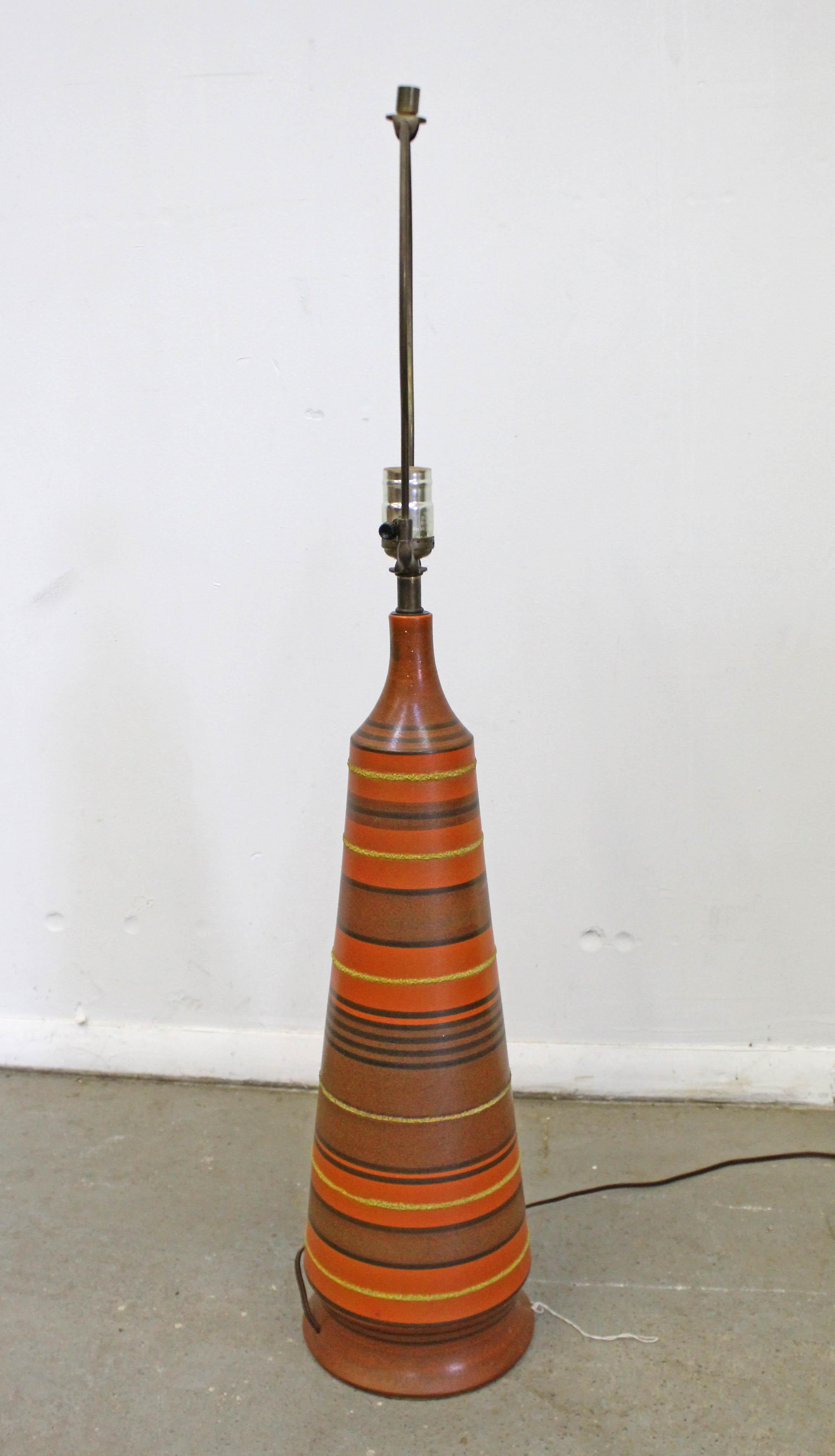 Offered is a vintage Mid-Century Modern table lamp from Italy. This lamp has a retro look with a conular shape, featuring orange pottery with textured stripes. It is in good, working condition given its age with minor marks/scratches on the base and