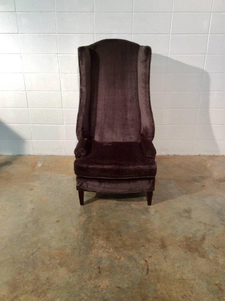 A unique pair of monumental wing back chairs. These would be great to add some height to a room plus make a statement. These chairs have been restored including refinished legs, new foam and luxurious brown upholstery.