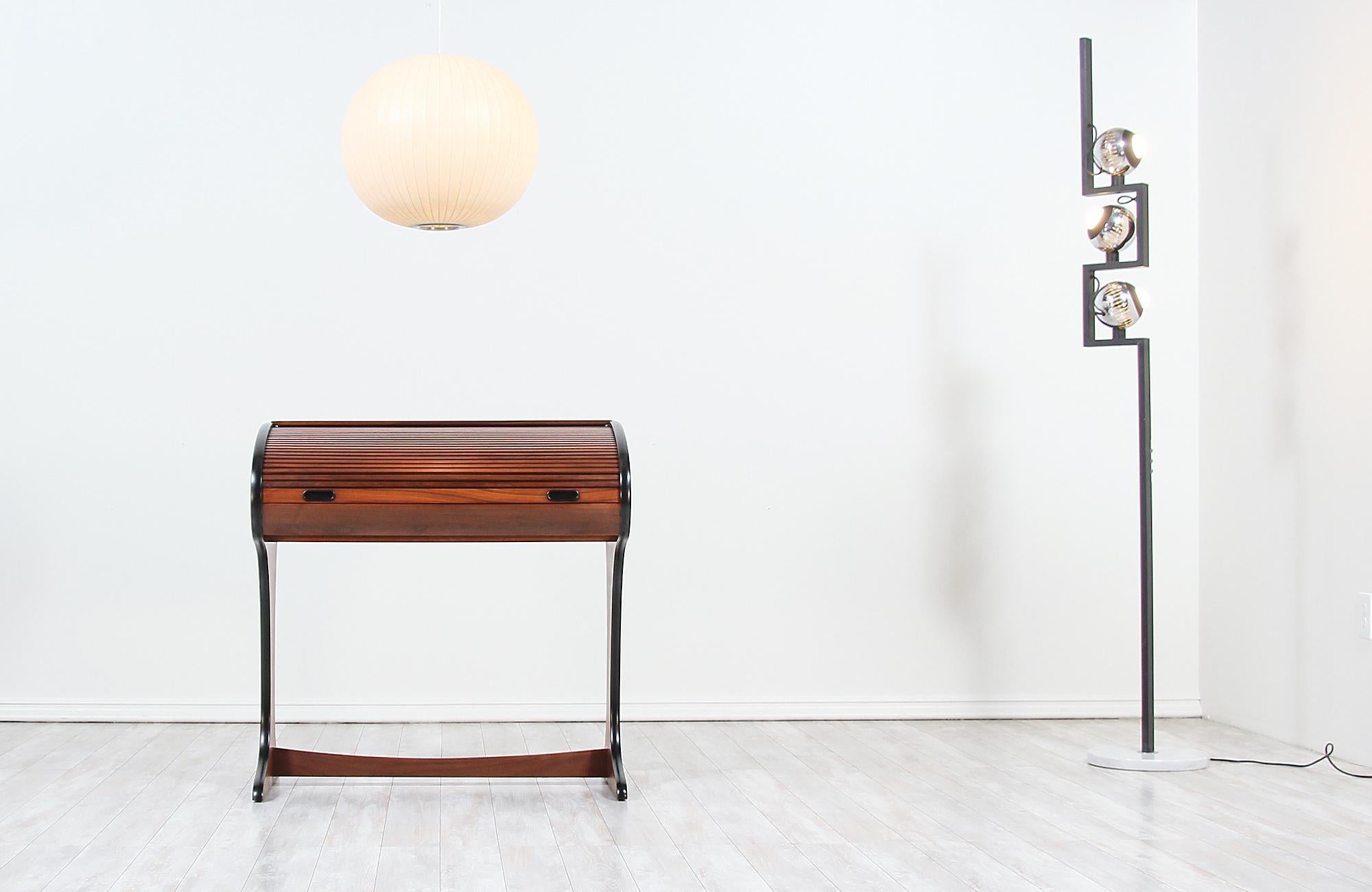Elegant vintage writing desk designed and manufactured in the United States, circa 1960s. This rare piece features a walnut wood case with roll-top tambour-doors that slide back revealing a writing surface. Its fitted interior offers plenty of