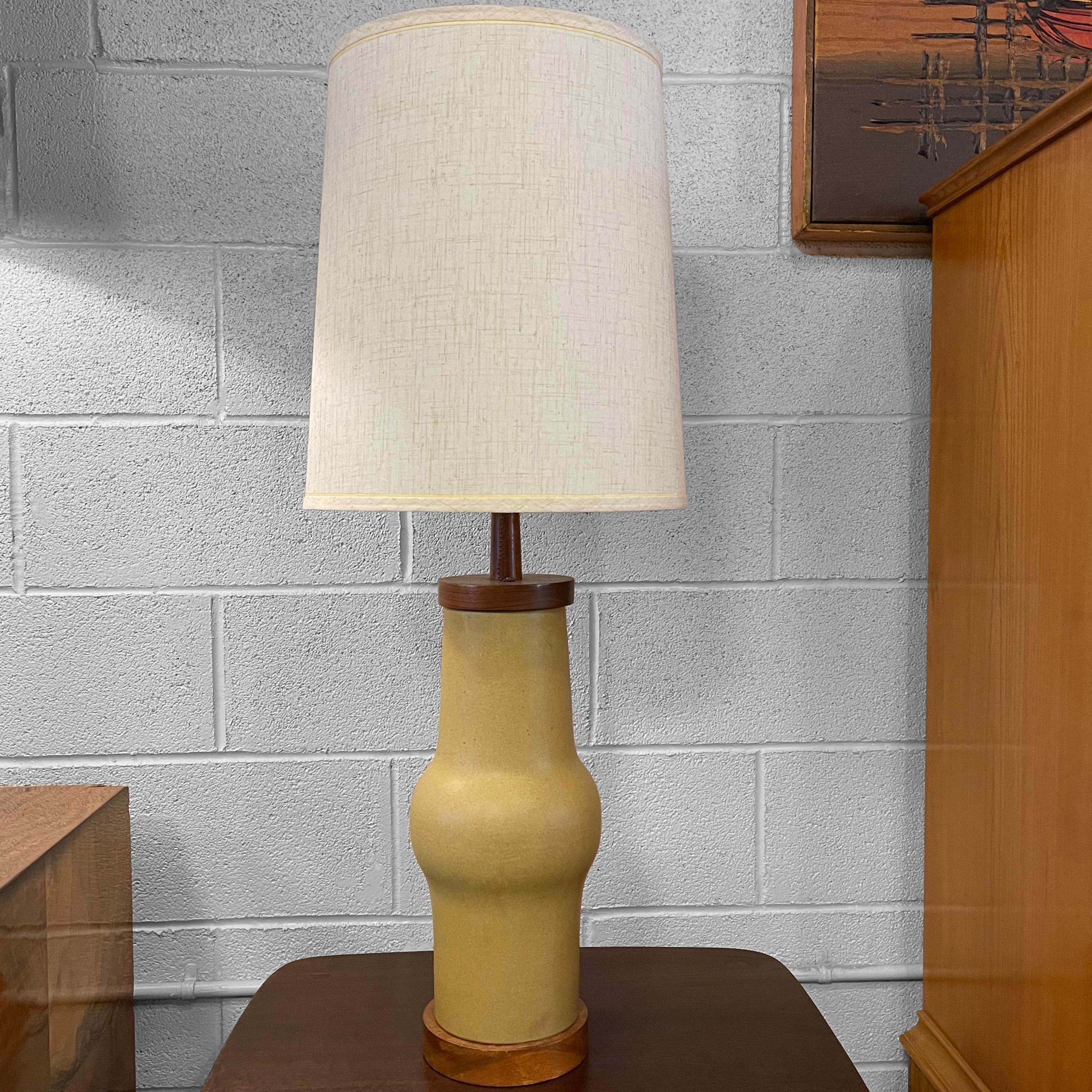 Mid-Century Modern, art pottery, table lamp by Gordon Martz for Marshall Studios features an organically shaped, matte glaze, tan ceramic base with walnut accents and brass hardware. The lamp measures 24 inches to the socket. The shade shown can be