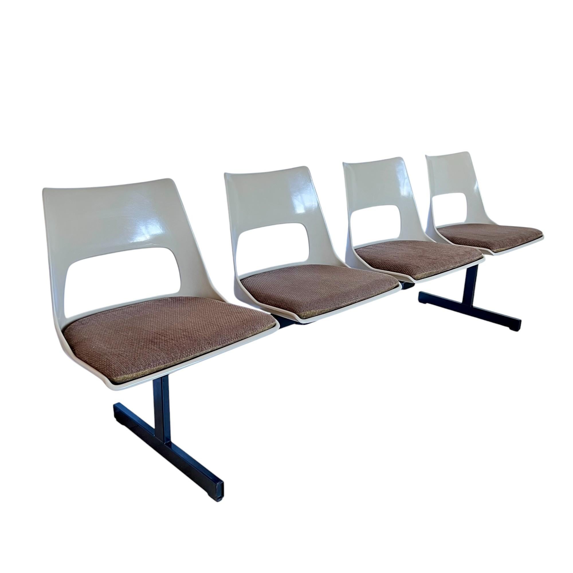 Vintage mid-century modern tandem beam seating by Krueger International circa 1969. This bench features four molded fiberglass light beige color shells connected on a black steel stretcher frame. The fiberglass seats are vented and slotted for