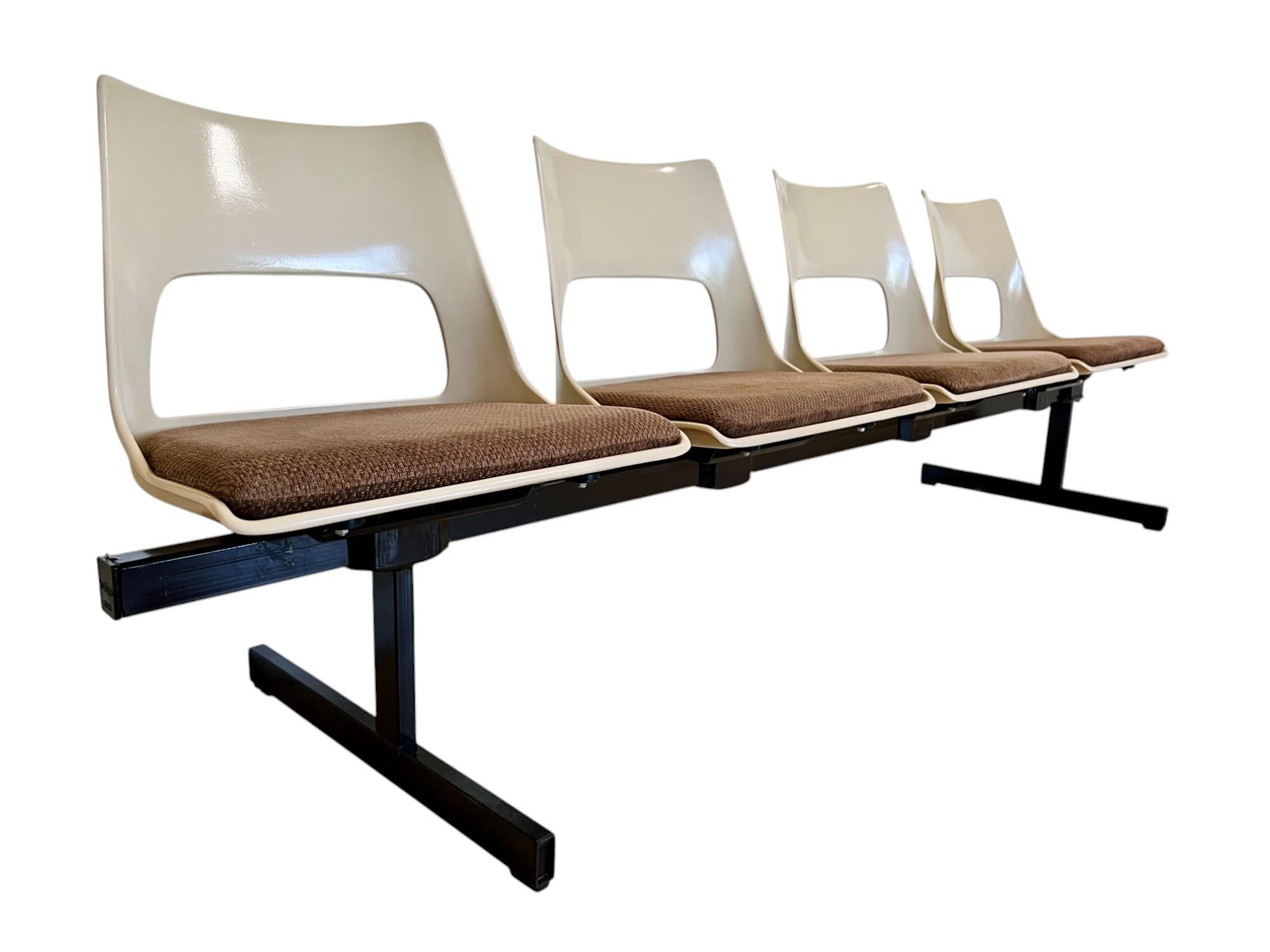 Vintage mid-century modern tandem beam seating by Krueger International circa 1969. This bench features four molded fiberglass light beige color shells connected on a black steel stretcher frame. The fiberglass seats are vented and slotted for