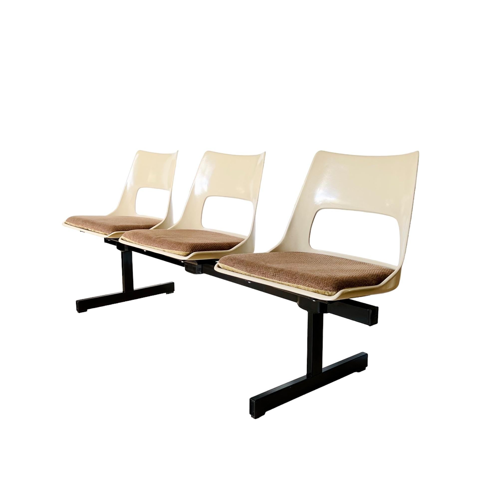 Vintage mid-century modern tandem beam seating by Krueger International circa 1970. This bench features three molded fiberglass light beige color shells connected on a black metal stretcher frame. The fiberglass seats are vented and slotted for