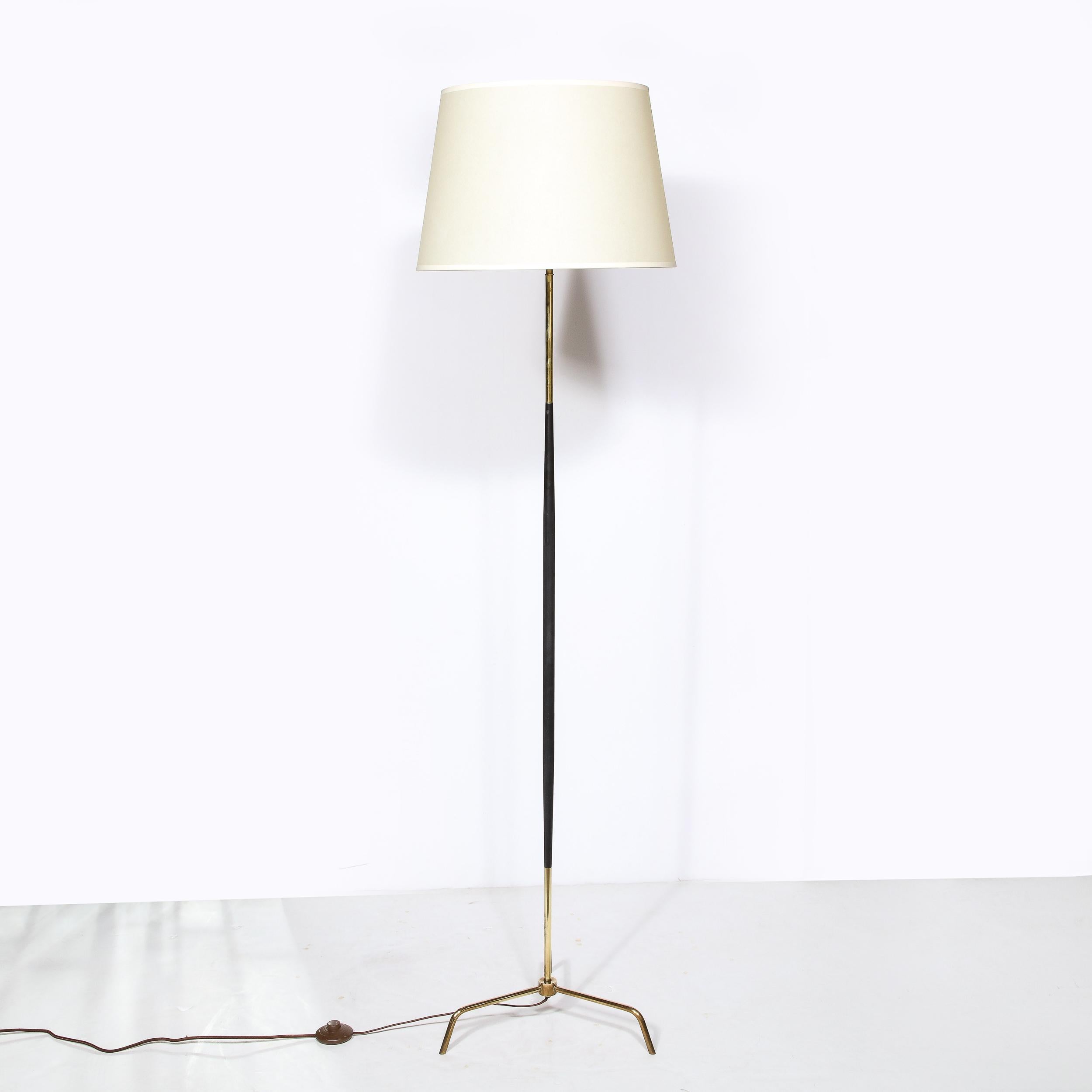 This elegant Mid-Century Modern floor lamp was realized in France circa 1950. It features a tripod style base in lustrous brass consisting of three elegantly apportioned feet arched like bird talons and supporting the body of the lamp. The stem of