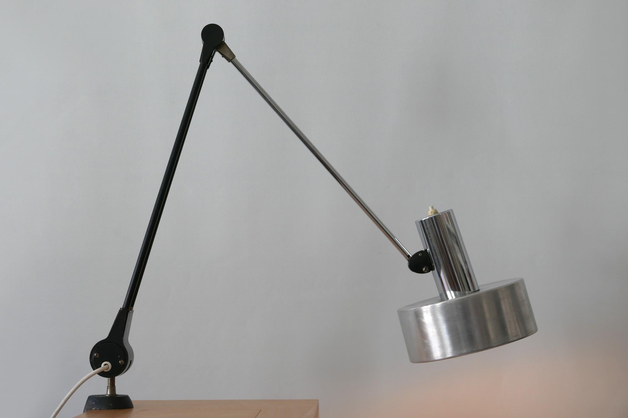 Articulated Mid-Century Modern task lamp or clamp table light. Model 6933. Designed and manufactured by Kaiser Leuchten, 1970s, Germany.

Executed in steel and aluminium, the lamp needs 1 x E27 Edison screw fit bulb, is wired and in working