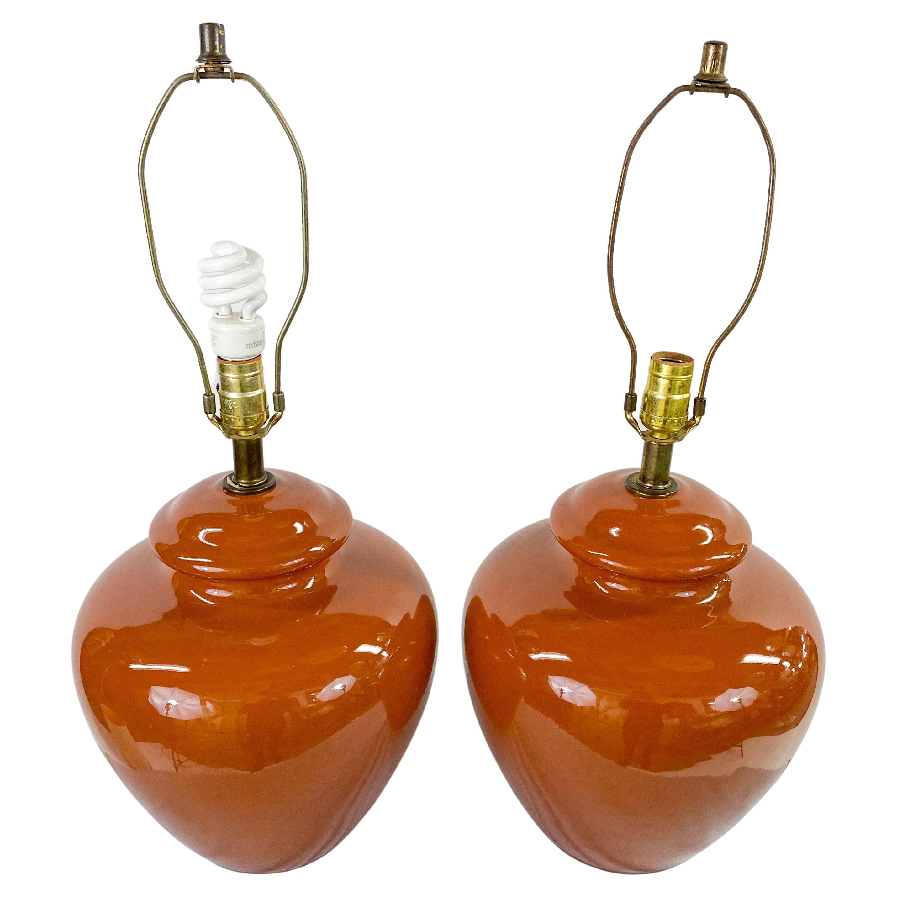 A pair of Mid-Century Modern table lamps. Timeless in style, the lamps are made of ceramics in an oval shape and featuring a tawny brown color. Both lamps are wired and in working condition. 

Dimensions: 25