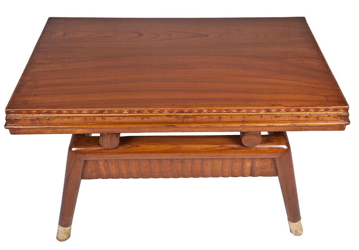 A Mid-Century Modern teak coffee table with mahogany inlay around the top edge on all four sides. Brass feet and rippled carved work along the base.