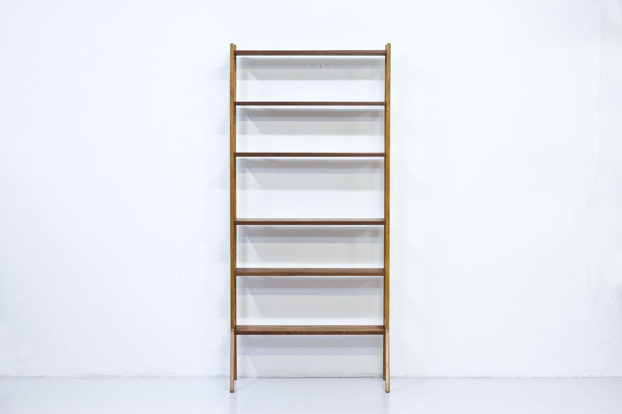 Freestanding shelving system made in Sweden during the 1950s. Oak frame with teak shelves, brass details.