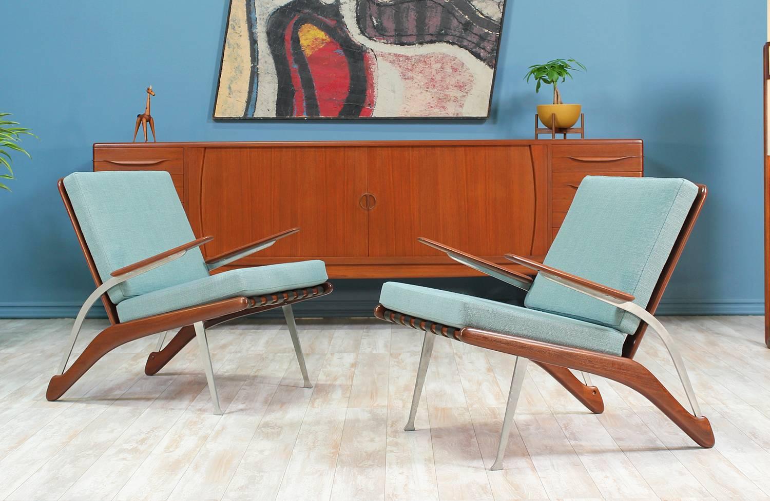 Mid Century Modern lounge chairs designed and manufactured in the United States circa 1960’s. Featuring a sculpturally carved teak wood combined with a steel frame, which shows light patina. The new high-density cushions have been upholstered in a