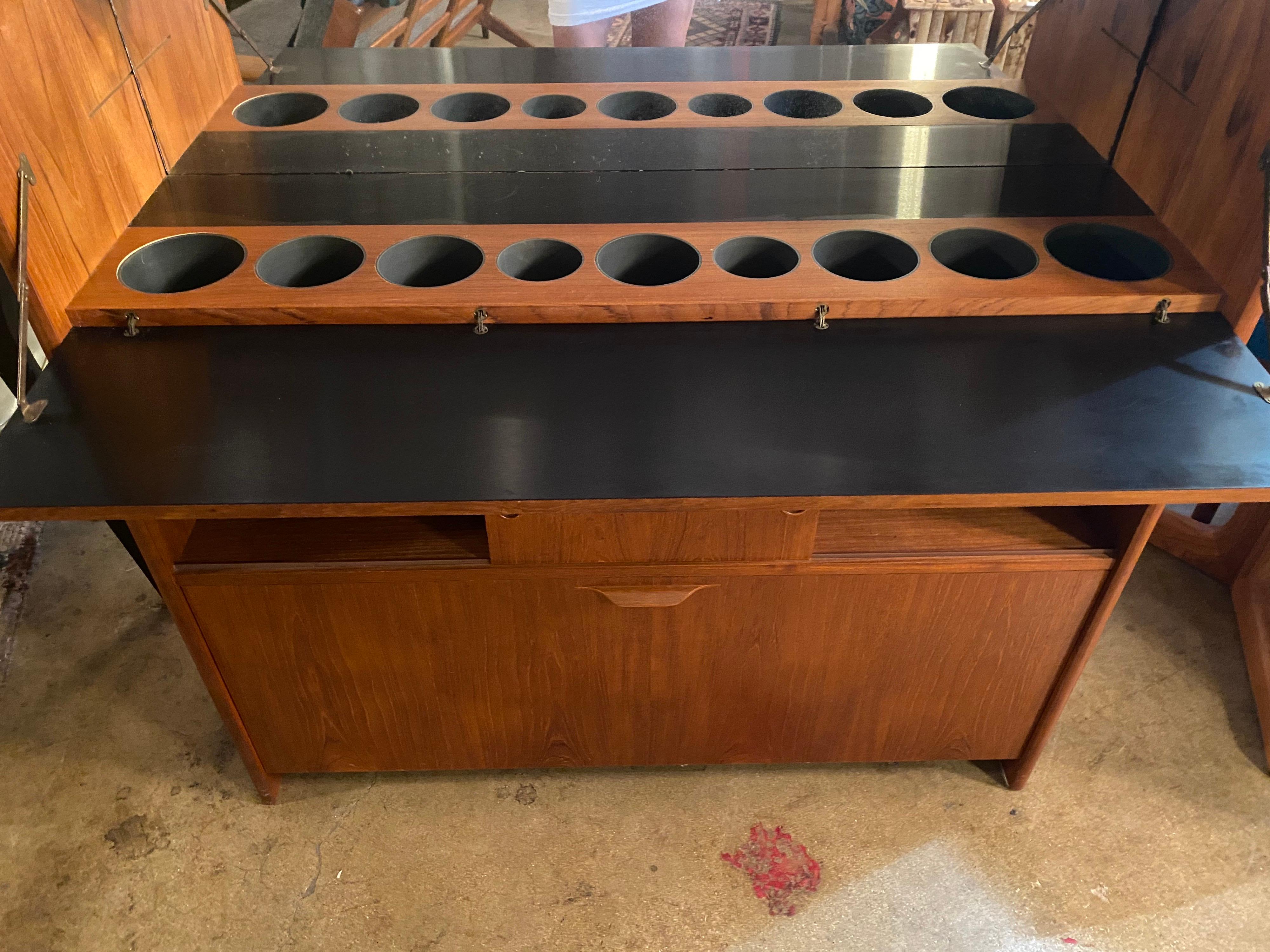 Gorgeous danish modern teak bar designed by Johannes Andersen features round inlays in the front and back along with compartments for glass and bottles. This mid-century bar is in great overall condition.