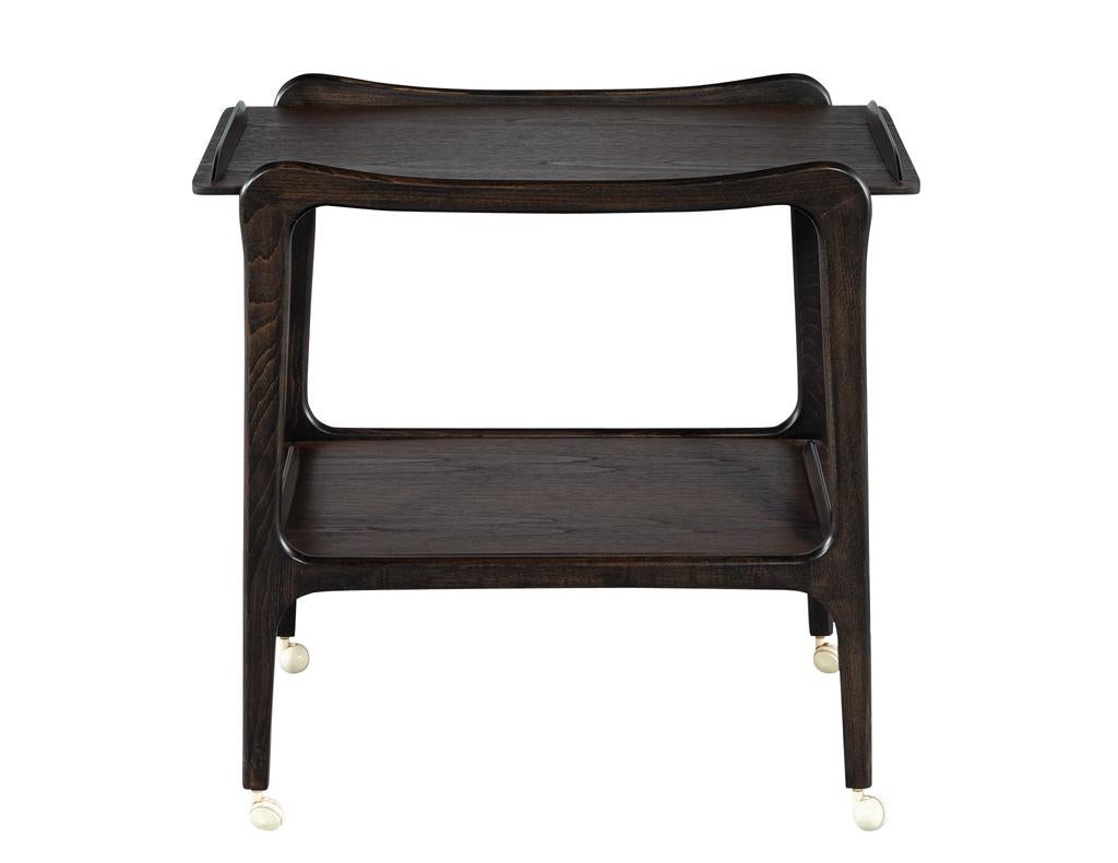 Remontez le temps avec ce superbe chariot de bar moderne du milieu du siècle, véritable témoignage du design américain des années 1970. Fabriqué en teck dans une riche finition de noyer brun, ce meuble dégage chaleur et sophistication. Son espace de