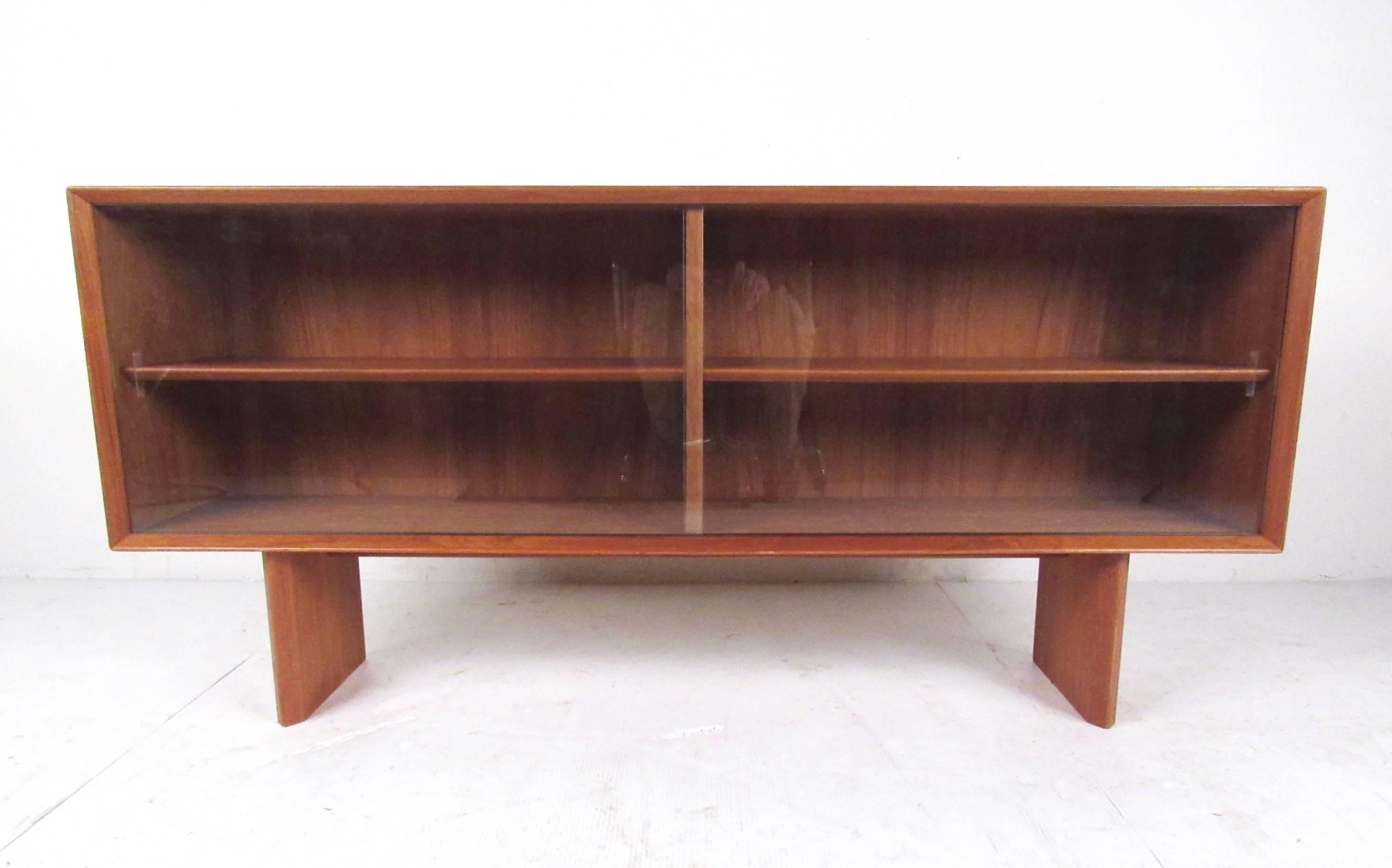 This Scandinavian teak book case by Falster offers adjustable shelf storage behind sliding glass doors. Danish modern design showcased with the rich Teak finish of the piece. Perfect display storage shelf for home or business use. Please confirm