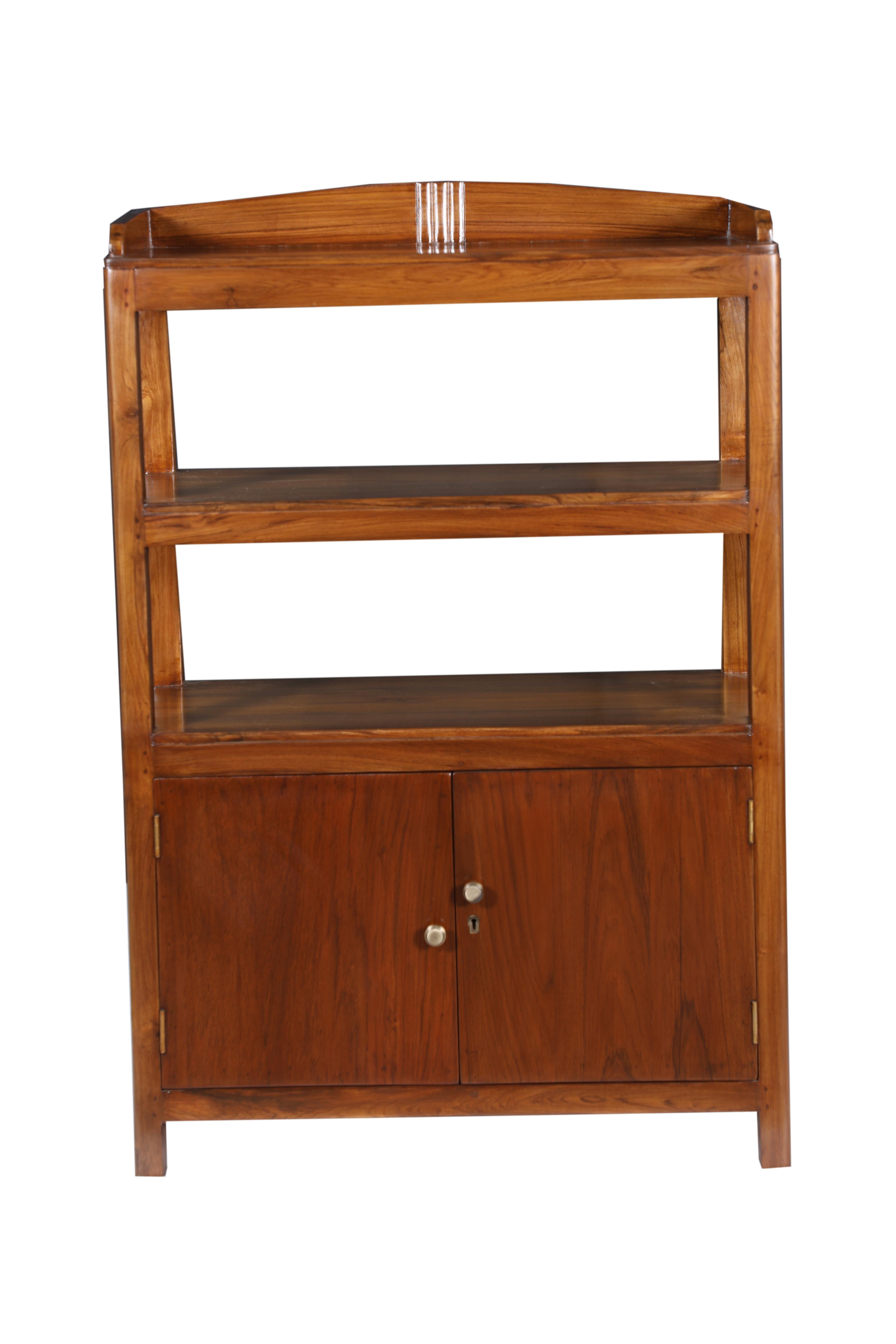A Mid-Century Modern combination teak bookcase shelves and cabinet at the lower third. Offset brass knobs on the front doors of the cabinet portion. Carved detail at the top crest. Circa 1970's.