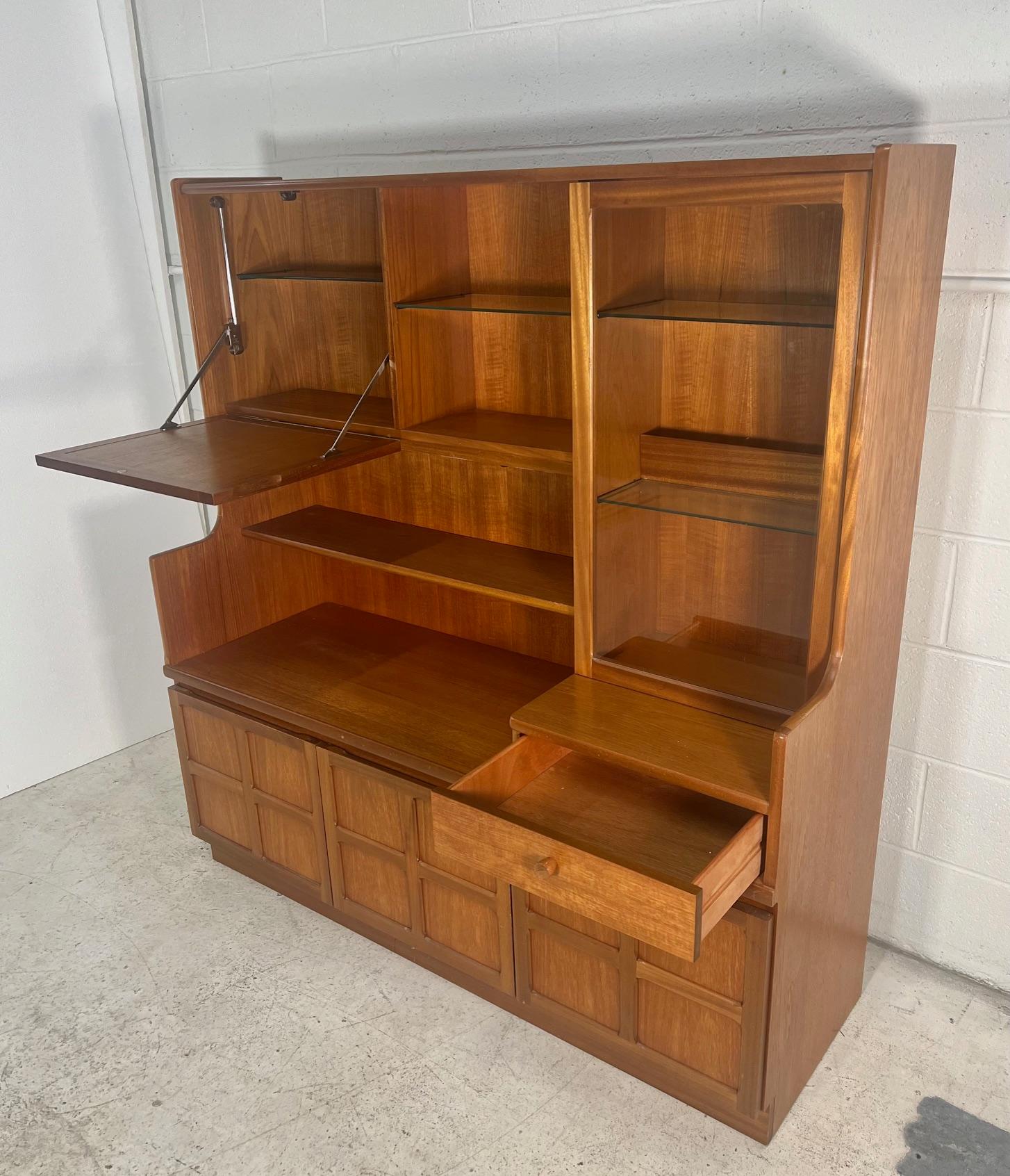 Gorgeous Mid Century Modern teak buffet. Made by Nathan Furniture UK.

Featuring adjustable glass shelves and a drop down bar at the top.

Very good condition. Stains inside right bottom cabinet. Some marks on the left side. Other minor marks here
