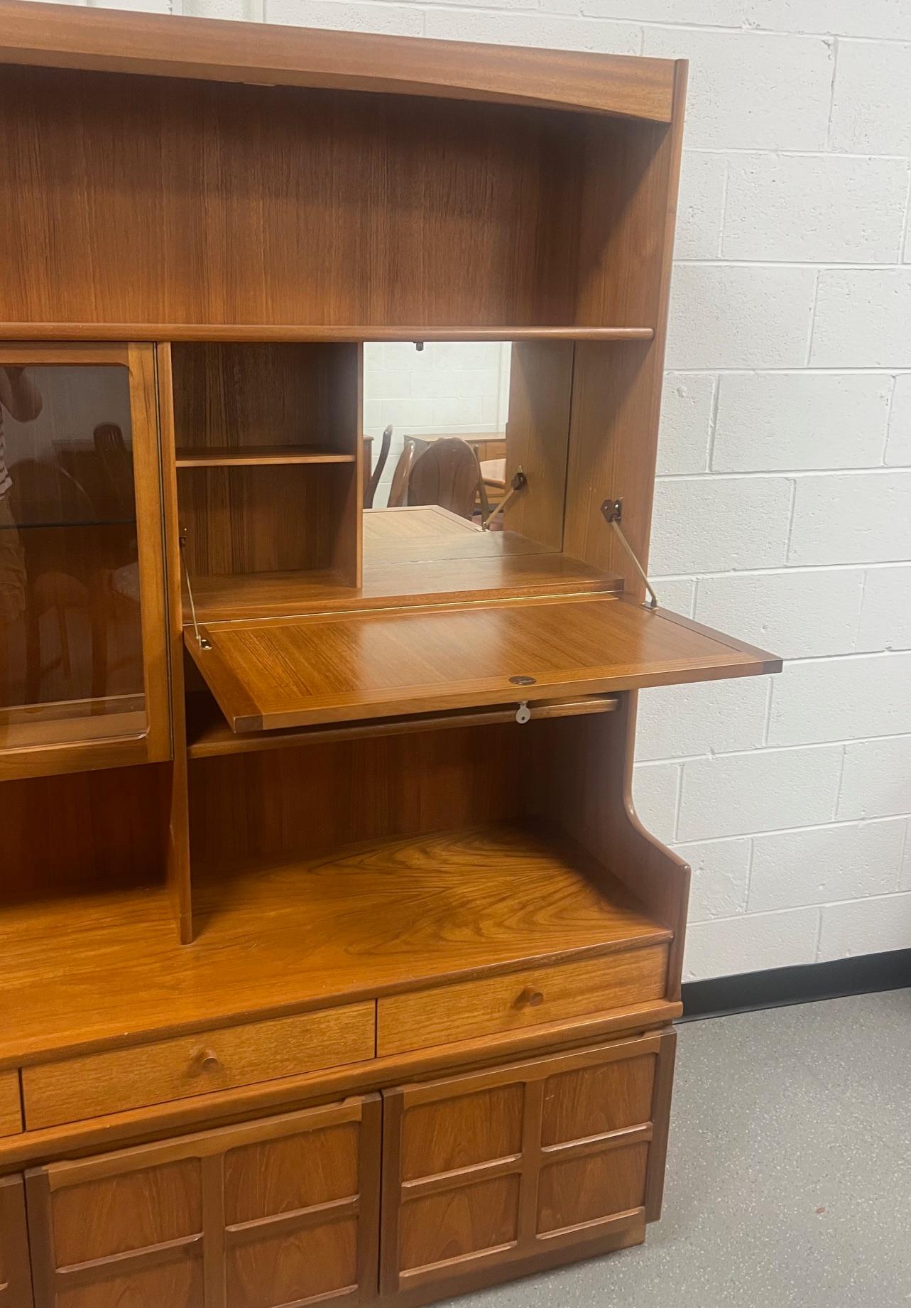 Gorgeous Mid Century Modern teak buffet. Made by Nathan Furniture UK.

Featuring an adjustable glass shelf and a drop down bar at the top. Three drawers in the middle and cabinet storage shelf at the bottom. Fixed shelf inside the right bottom