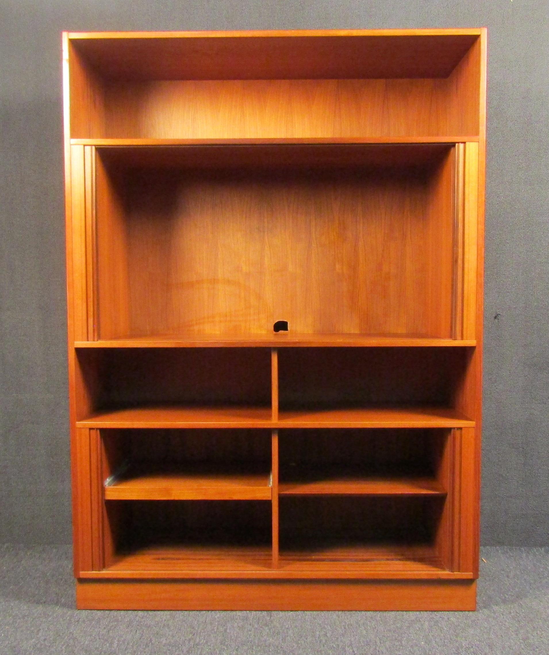 Armadio moderno vintage in teak che offre un ampio spazio di archiviazione dietro un'elegante serie di ante a tamburo con uno spazio superiore e centrale per piccoli oggetti da esposizione. Questo mobile a parete si adatta perfettamente a qualsiasi