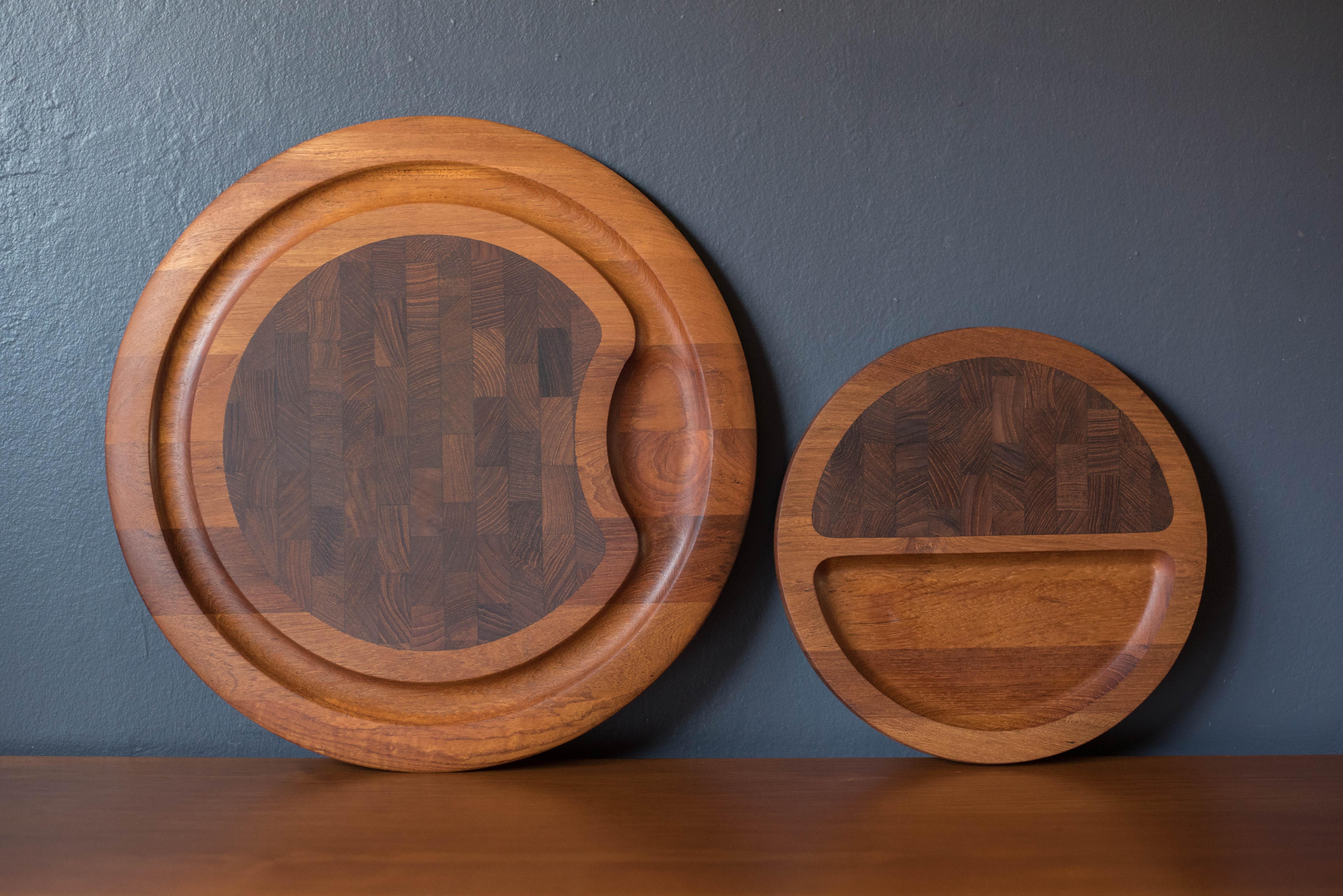 Vintage Danish round cutting board tray in teak designed by Jens Quistgaard for Dansk. This collectible piece is crafted of thick solid planked teak with deep grooves intended to use as a prep work board and serving dish. Features a hardwood end