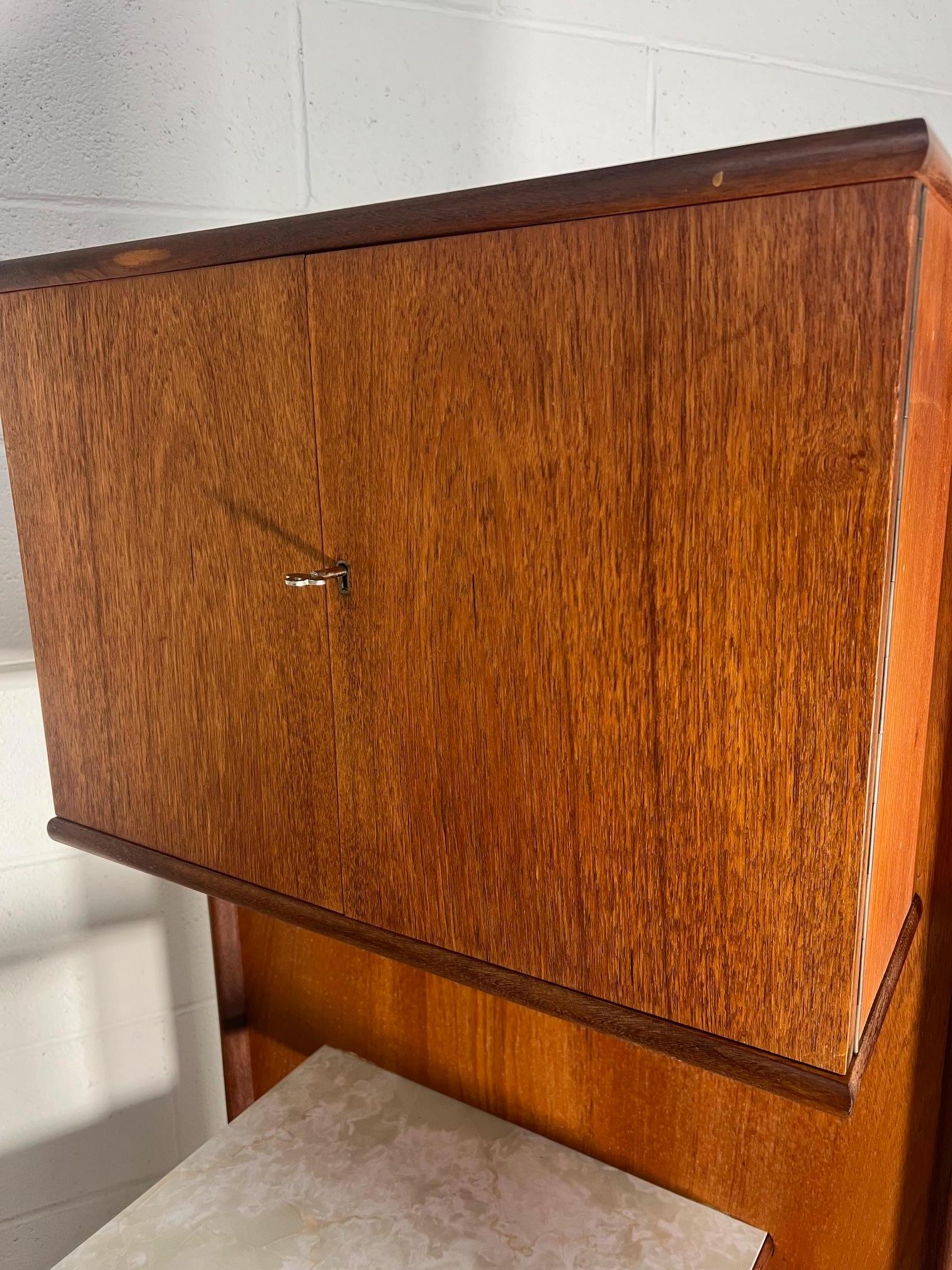 This is an amazing 1970's teak cocktail bar by Turnidge of London. Made in England.

The side panel can be placed on the left or right side. The top has a white marble effect finish.

Very nice condition overall. Some stains on the front and a