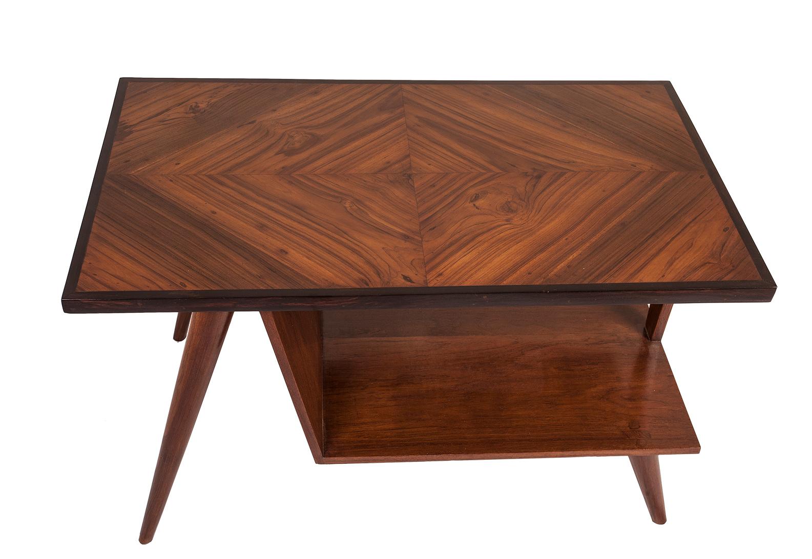 A Mid-Century Modern teak wood coffee table with a rosewood border. Great use of the wood grains on the top. Tapered legs. Lower shelf measures 10