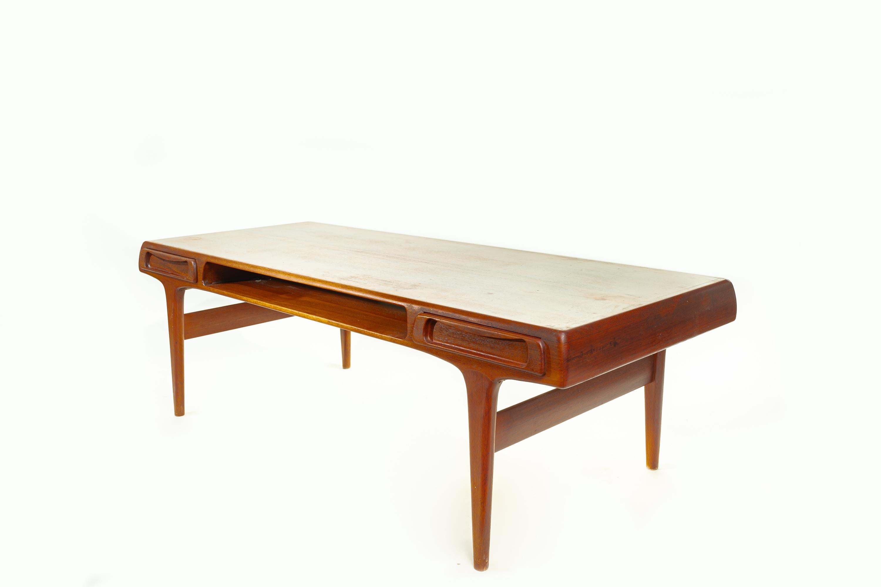 Classic Scandinavian modern mid-century coffee table design by Johannes Andersen. The table is made of solid teak, and it features two side drawers and an open compartment in the middle.

The table is a perfect example of Andersen's signature style.